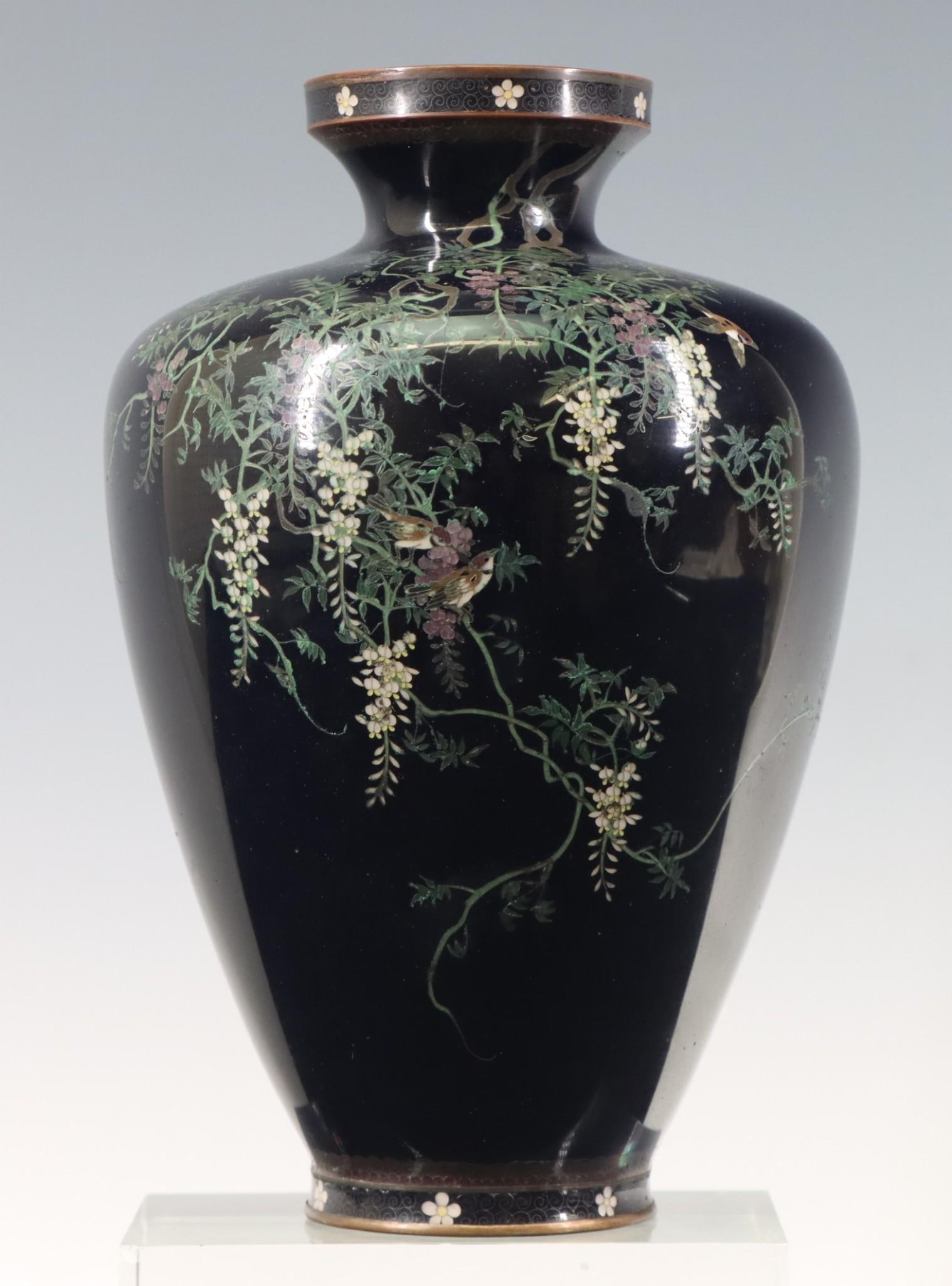 Hayashi Chuzo Japanese Cloisonne Vase: Meiji - Taisho era silver wire cloisonne vase decorated birds among white and purple wisteria on a black ground, the mouth and foot decorated with rosettes and wire scrolls. Stamped mark for Hayashi C