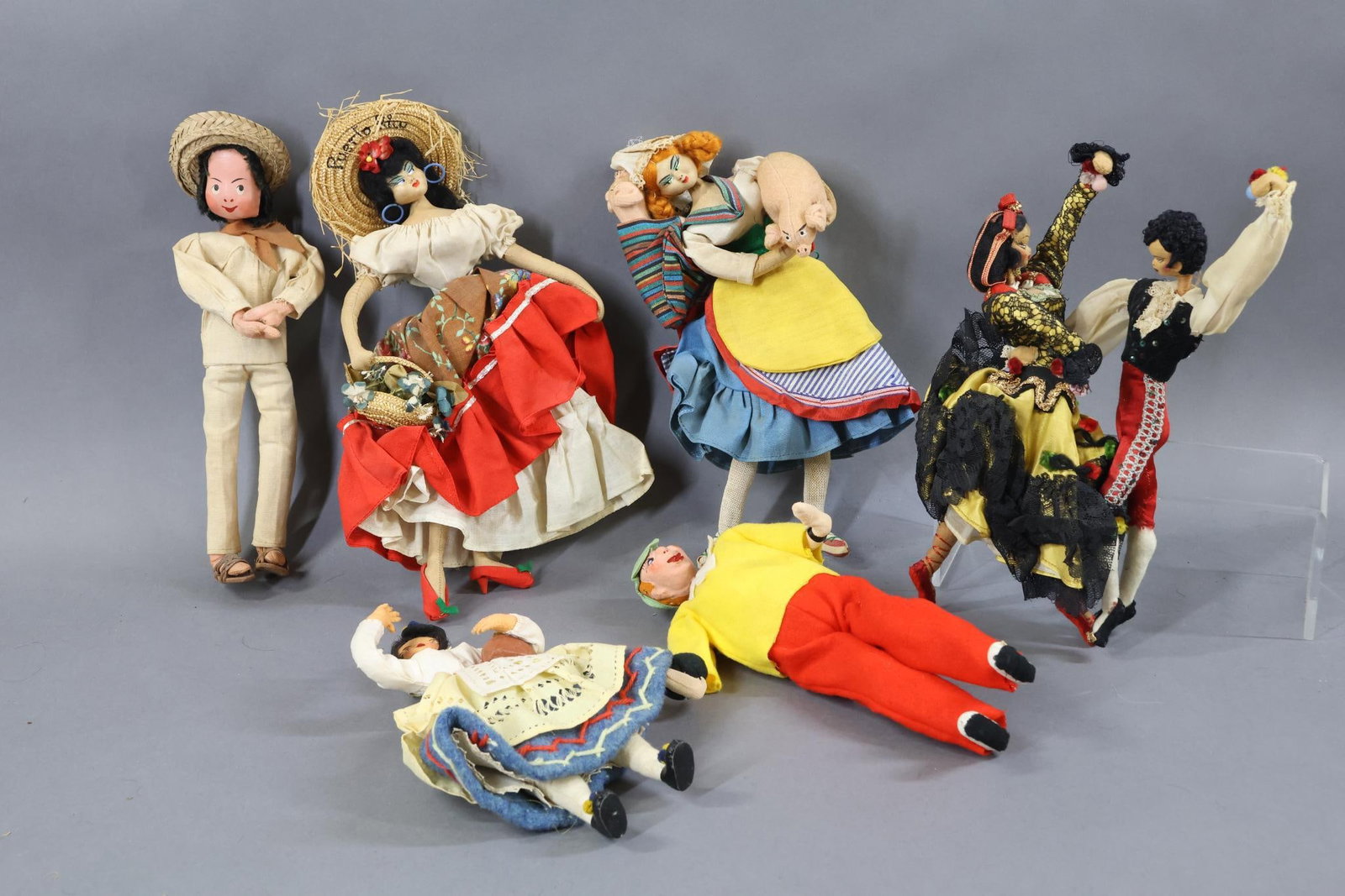 CLOTH/OTHER DOLLS.: LOT of (7) Unmarked KLUMPE/ROLDAN type dolls. 11" Dancing Spanish couple. 11" Lady holding pig and one in her backpack. 11" Lady from Puerto Rico. 8" Lady marked "Cafier" holding a basket of fruit. Th