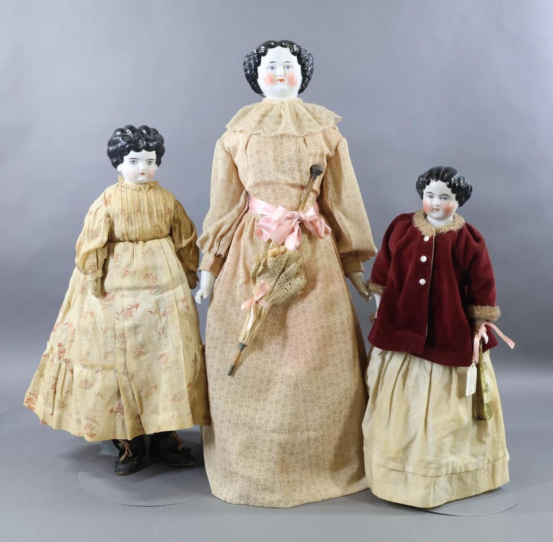 CHINA, PARIAN DOLLS.: LOT of (3) China shoulder head dolls. All of the dolls have black center part hairstyles, painted blue eyes and are dressed in vintage/antique clothing. They have cloth bodies, (2) have china lower li