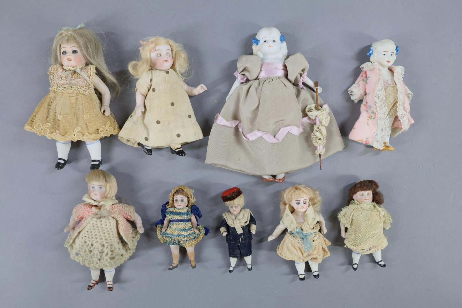 ALL BISQUE.: LOT of (9) dolls. All of the dolls have painted shoes/socks. (2) Have painted eyes, hair, painted blue bows in hair. NOTE: (1) has a cloth body. Both were Made in JAPAN. (1) Has painted eyes, a swivel