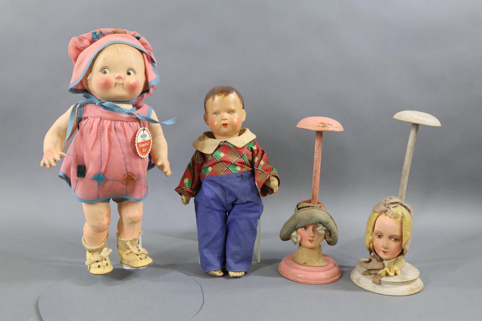 COMPOSITION/OTHER DOLLS.: LOT. (2) Dolls and (2) Hat Stands. Dolls - 13" Tagged PETITE Doll "Campbell Kid" Girl. Marked with cloth tag on back of dress and paper tag pinned on front of dress. Organdy clothing and oilcloth shoe