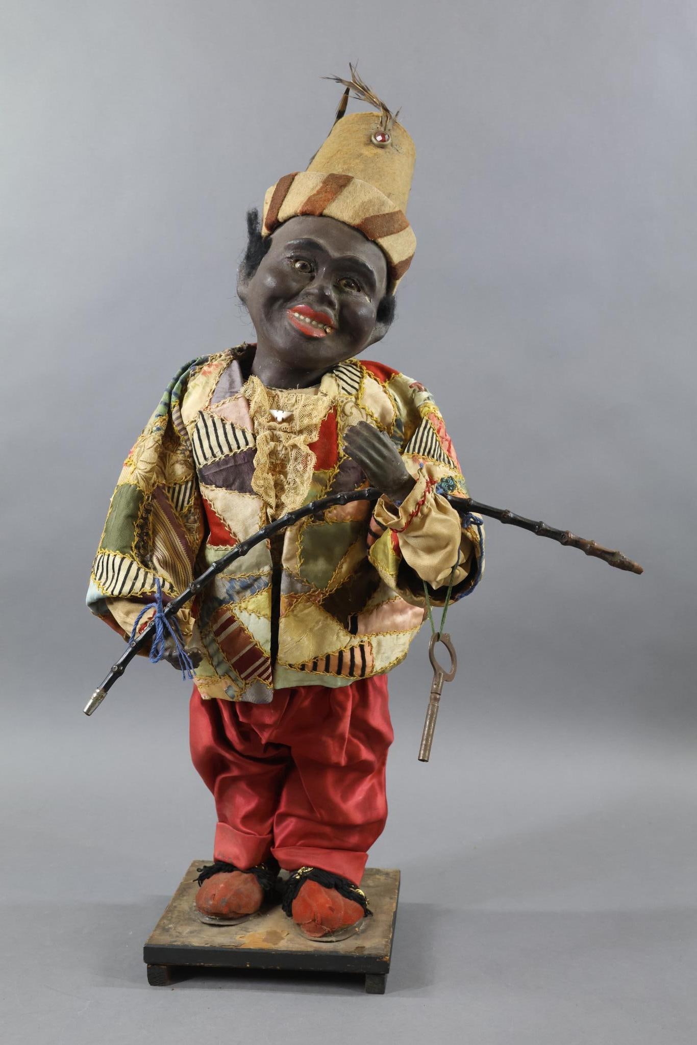 NOVELTY DOLLS/TOYS.: Black "NIDDY NODDER". 24" Figure on a 1" wooden base. Papier mache head with stationary glass eyes. Black mohair wig. Open/closed mouth showing (6) painted teeth. Papier mache hands, red "leather" sho