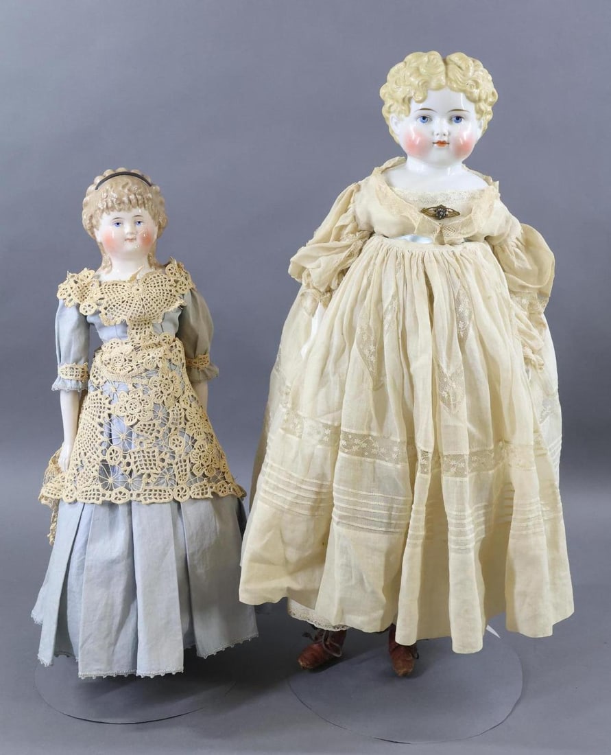 CHINA, PARIAN DOLLS.: Pair of China shoulder head dolls. Both dolls have blonde hair, painted blue eyes. They are both dressed in antique clothing. Doll 1) 20 1/2" 1875 "Spill Curls". Pale pink tint on face and arms. Soft 