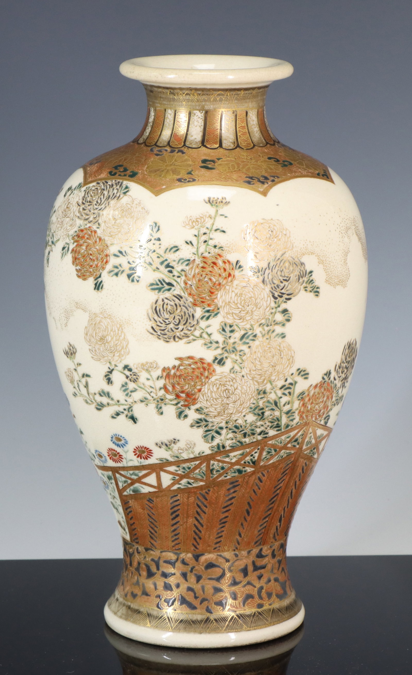Hosai Japanese Satsuma Pottery Vase: Meiji era vase decorated with chrysanthemums in a fenced garden, with a lower border of tendrils over crosshatching, and an upper border of imperial mons and foliage under polychrome gadroons under fe