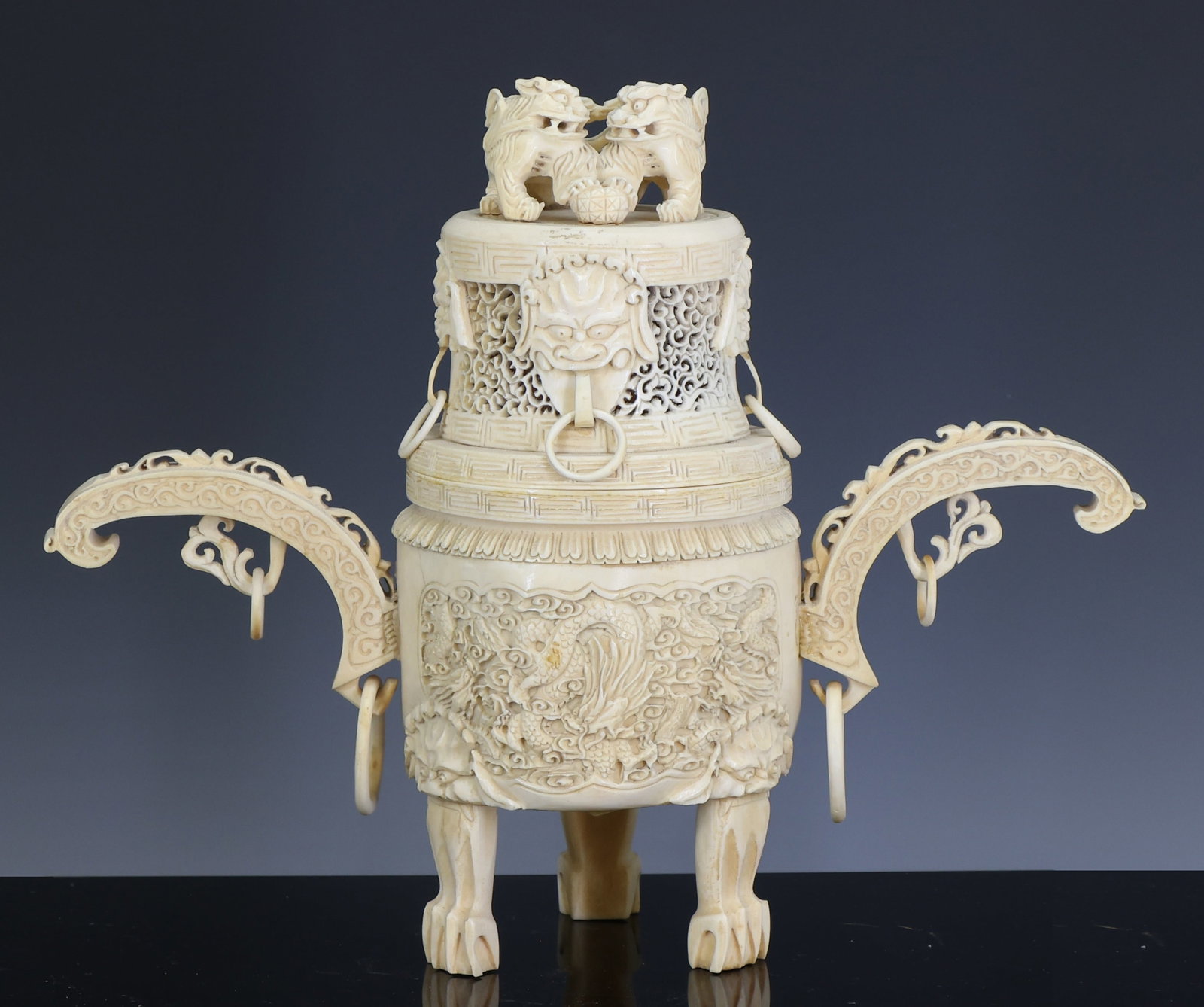 Chinese Carved Censer: Qing era censer decorated with relief carved panels depicting dragons in flight among clouds, and a cover with scrolling foliate openwork and four taotie mask and ring handles, surmounted by a double 