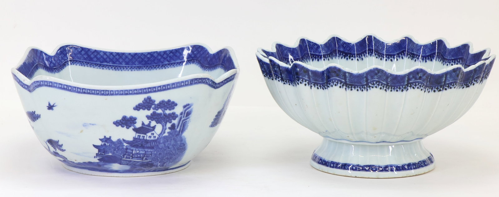 Chinese Nanking Porcelain Serving Bowls: Qing era blue and white export porcelain decorated with buildings, boats, birds, and mountain scenery, each with geometric, spearhead, and fish roe borders, including a footed and scalloped punch bowl