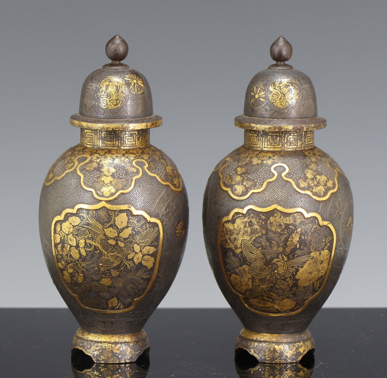 Asai Japanese Inlaid Iron Vases: Meiji era pair of parcel-gilt iron vases with complementing damascene / zogan silver inlay decoration, each with a panel to one side depicting birds hunting among flowers, and a panel to the other sid