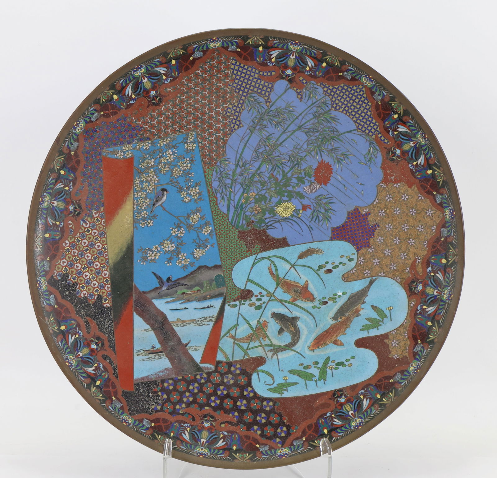 Japanese Cloisonne Charger: Meiji - Taisho era silver wire cloisonne on copper charger, decorated with panels in various forms depicting blue birds among cherry blossoms with night fishermen in the background, koi in a pond, and