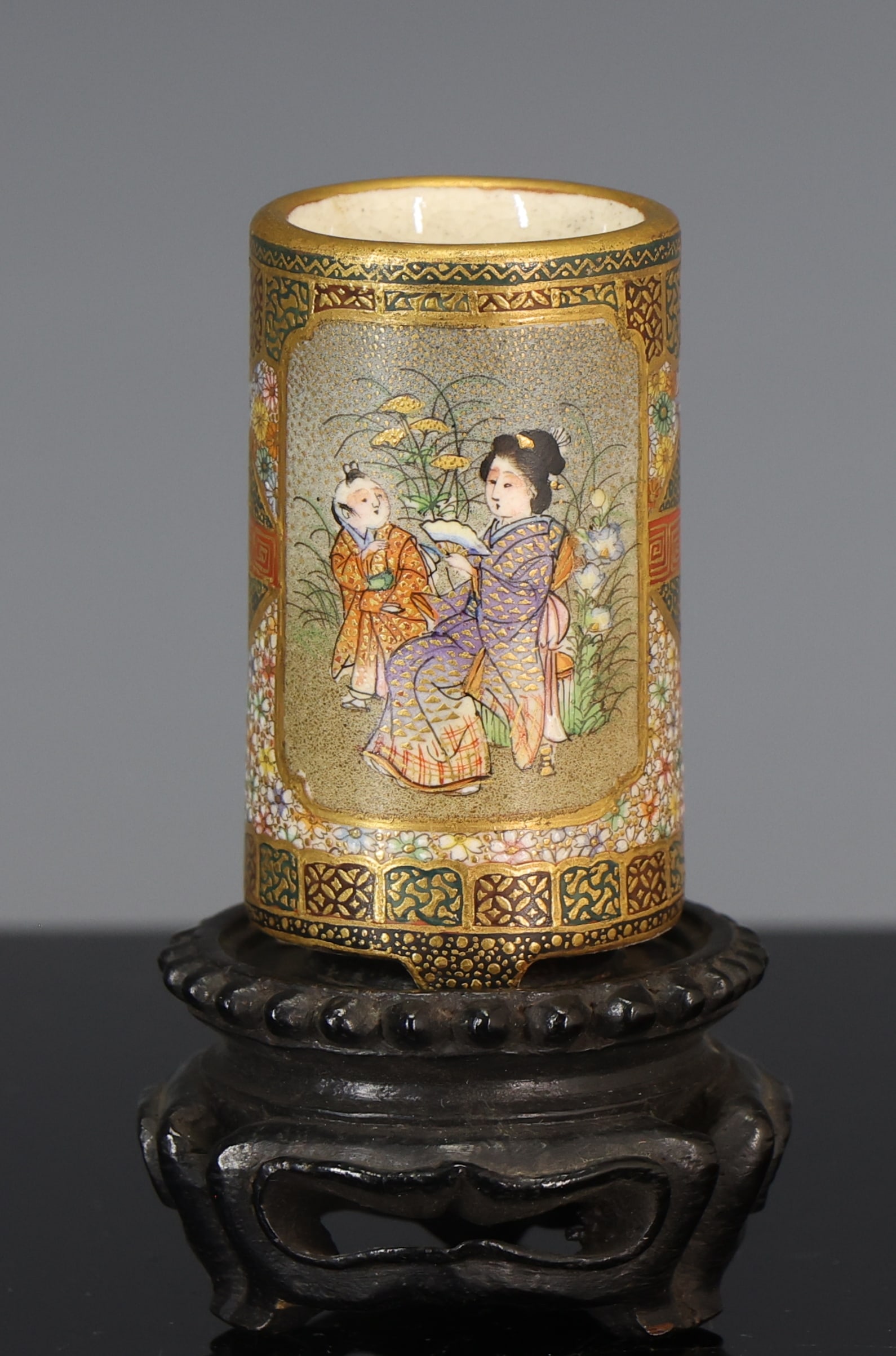 Kinkozan Japanese Satsuma Pottery Vase: Meiji - Taisho era miniature cylinder vase with a panel depicting children playing with precious objects, and another panel depicting a woman and a boy in a garden, each with orange peel grounds, surr
