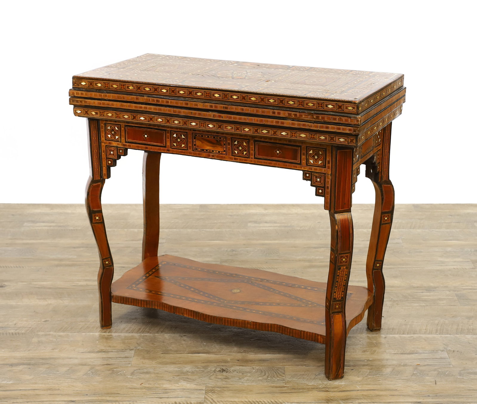 Syrian Parquetry Inlaid Games Table: Rosewood veneer and inlay with mother-of-pearl geometric and parquetry motifs opening to a green velvet playing surface opening to checker and backgammon playing boards, bottom tier, cabriole legs. La