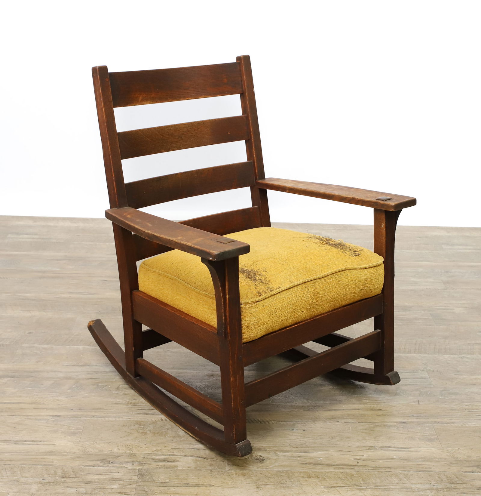 L. & J.G. Stickley Arts and Crafts Rocker: Quartersawn oak with a slatted back, bowed arms, tenon quadralinear posts with corbels, original worn textured fabric upholstery. 34"h x 27"w x 28"d, 17" seat height