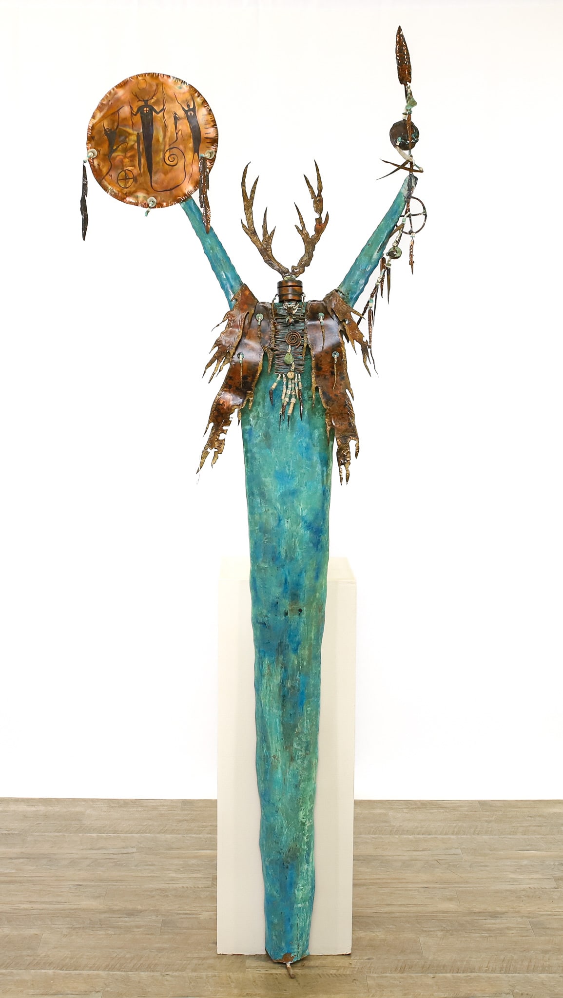 Patinated Shaman Sculpture Attr. Bill Worrell (1936 - 2021): Copper with forged antlers and vest and decorated with turquoise and bone accent jewelry, talisman, and other Native American dressware. Figural holding a spear and a copper plate drawing of figurals.