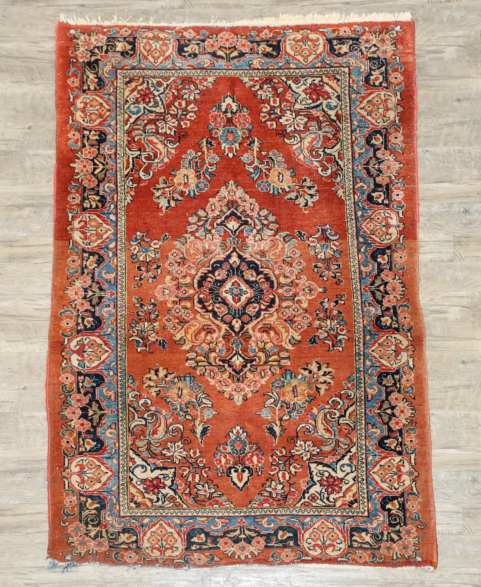 Persian Sarouk Rug: Hand knotted, cloud collar floral arabesque central medallion with pendants and hanging arrangements in a salmon field, rosette cream spandrels, floral cartouches in a navy and light blue main border.