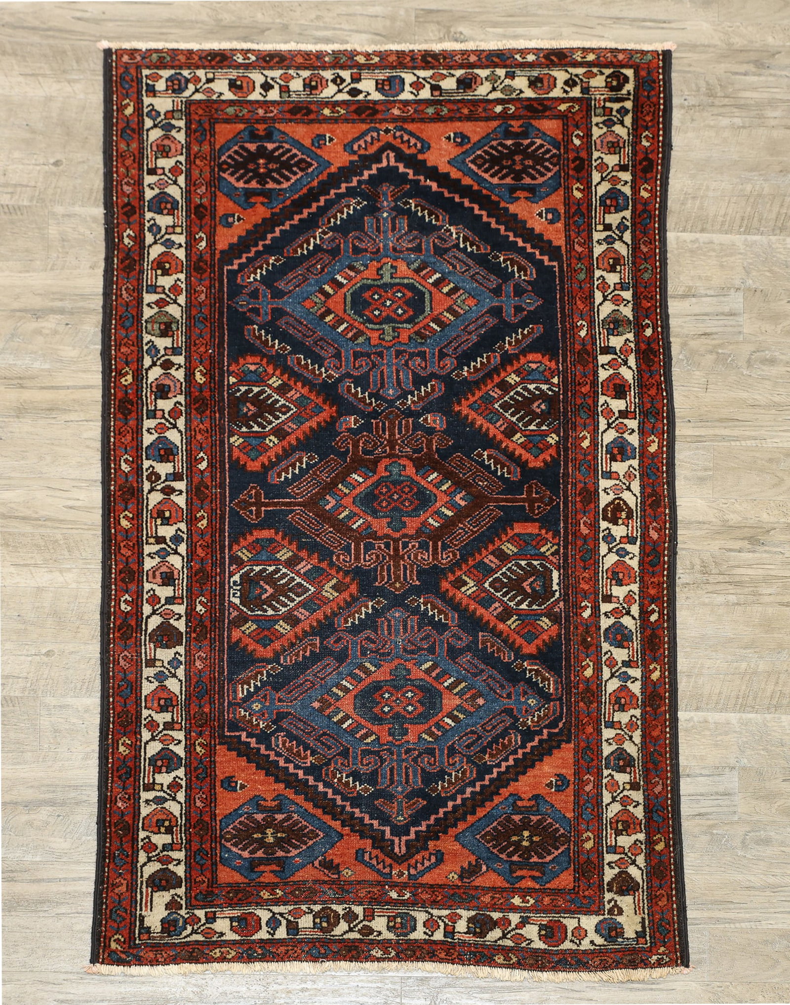 Persian Hamadan Rug: Hand knotted wool pile, triple diamond arabesque motif medallions in a blue field with surrounding arabesques and salmon ground in the spandrels, foliate and vine pattern in a cream main border. Early