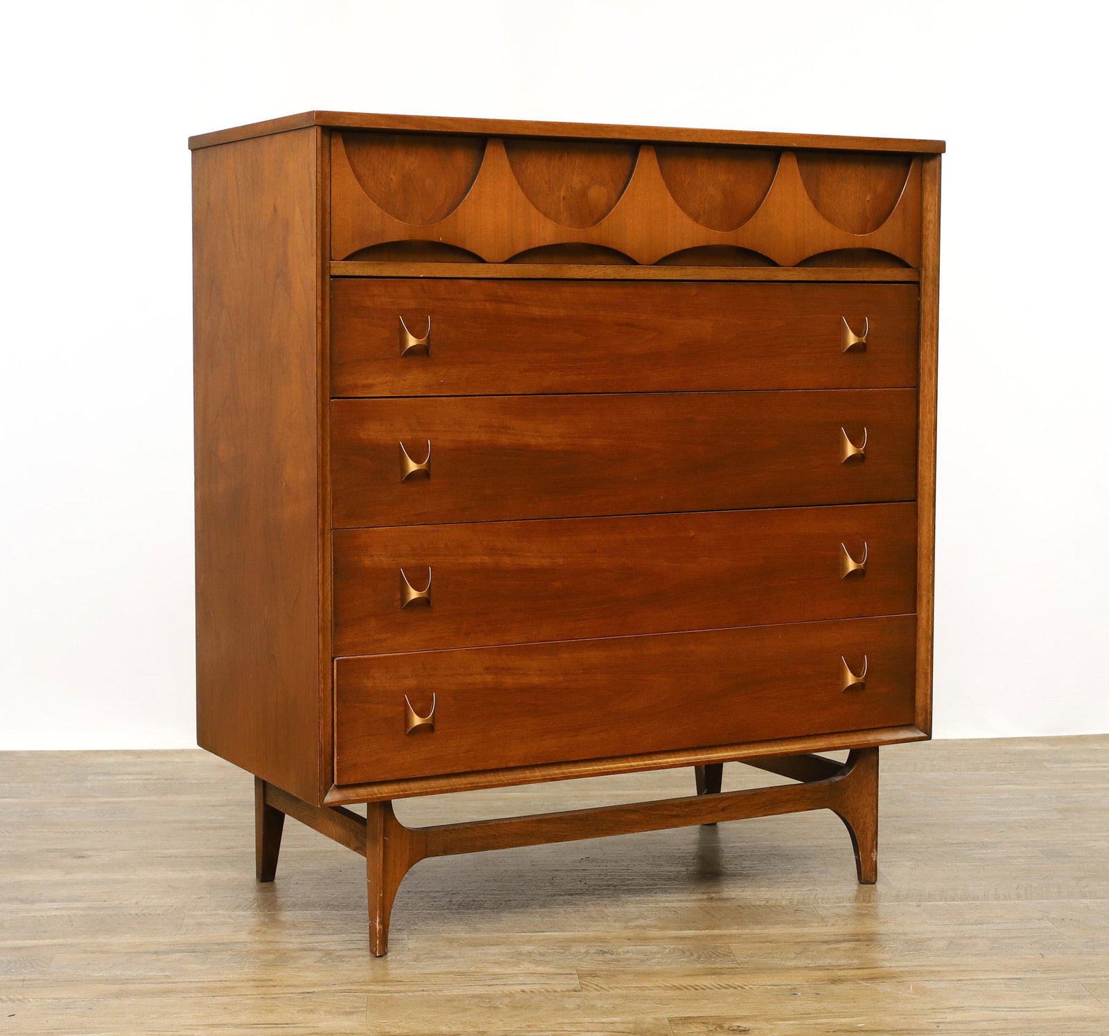 Broyhill Brasilia Chest of Drawers: Model 6130-40 walnut chest with a shaped drawer over four drawers with bronze tone pulls, mounted to a sculpted base. Labeled to the interior of a drawer and stamped en verso 6130/40 and L 502 65. Sca