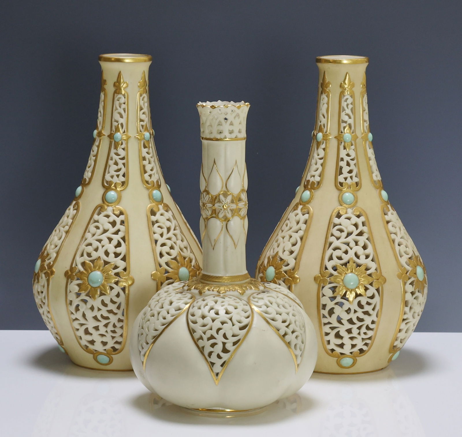 Grainger’s Worcester Porcelain Reticulated Vases: British porcelain vases with reticulated foliate and gilt decoration, including a pair with rosettes and turquoise faux jewels, and a complementing reeded example with rosettes, teardrops, and acanthu