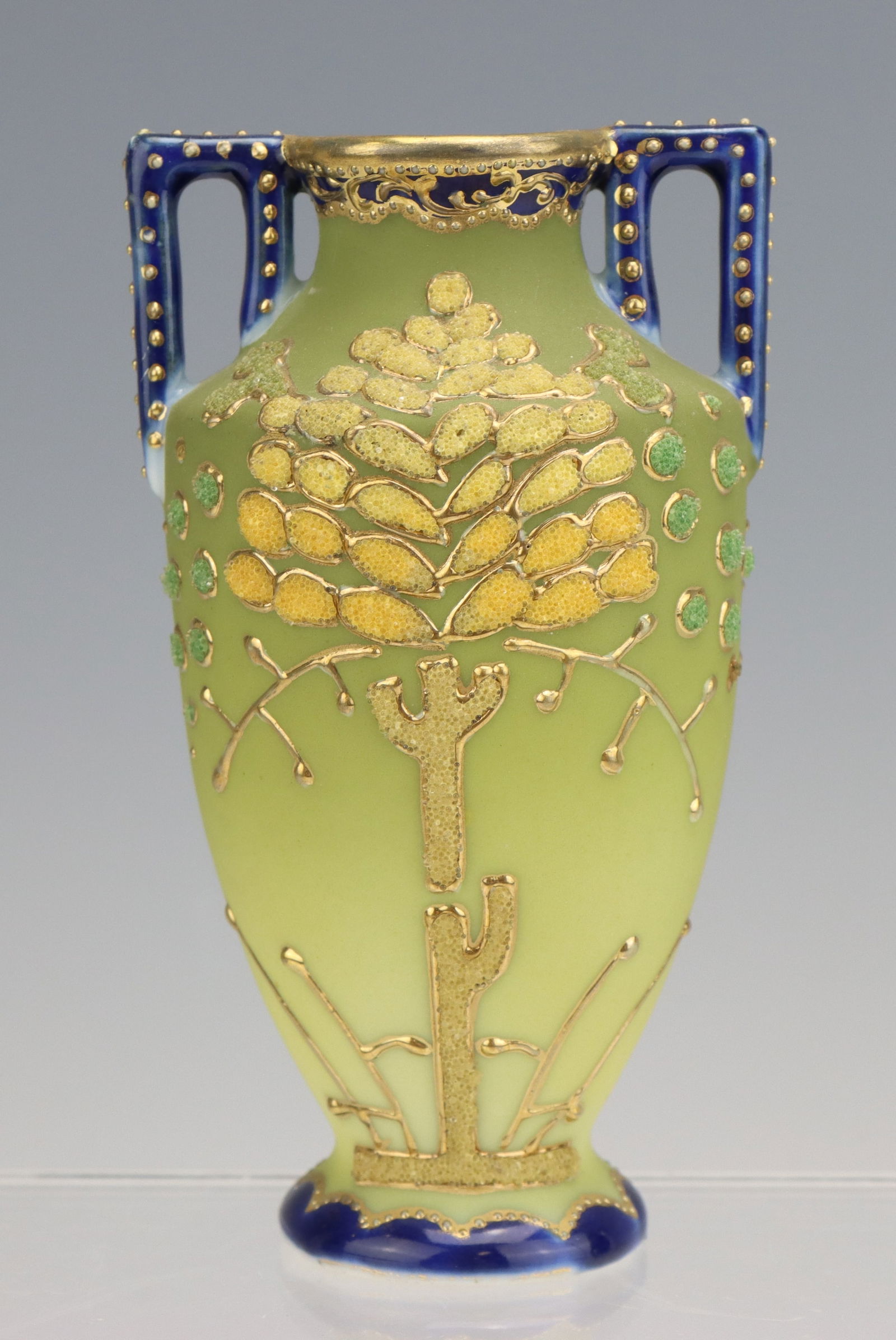 Nippon Porcelain Vase: Nippon porcelain bud vase, hand painted, gilt decorated tree design with cobalt handles, marked, 4.75"h x 2.75"dia.