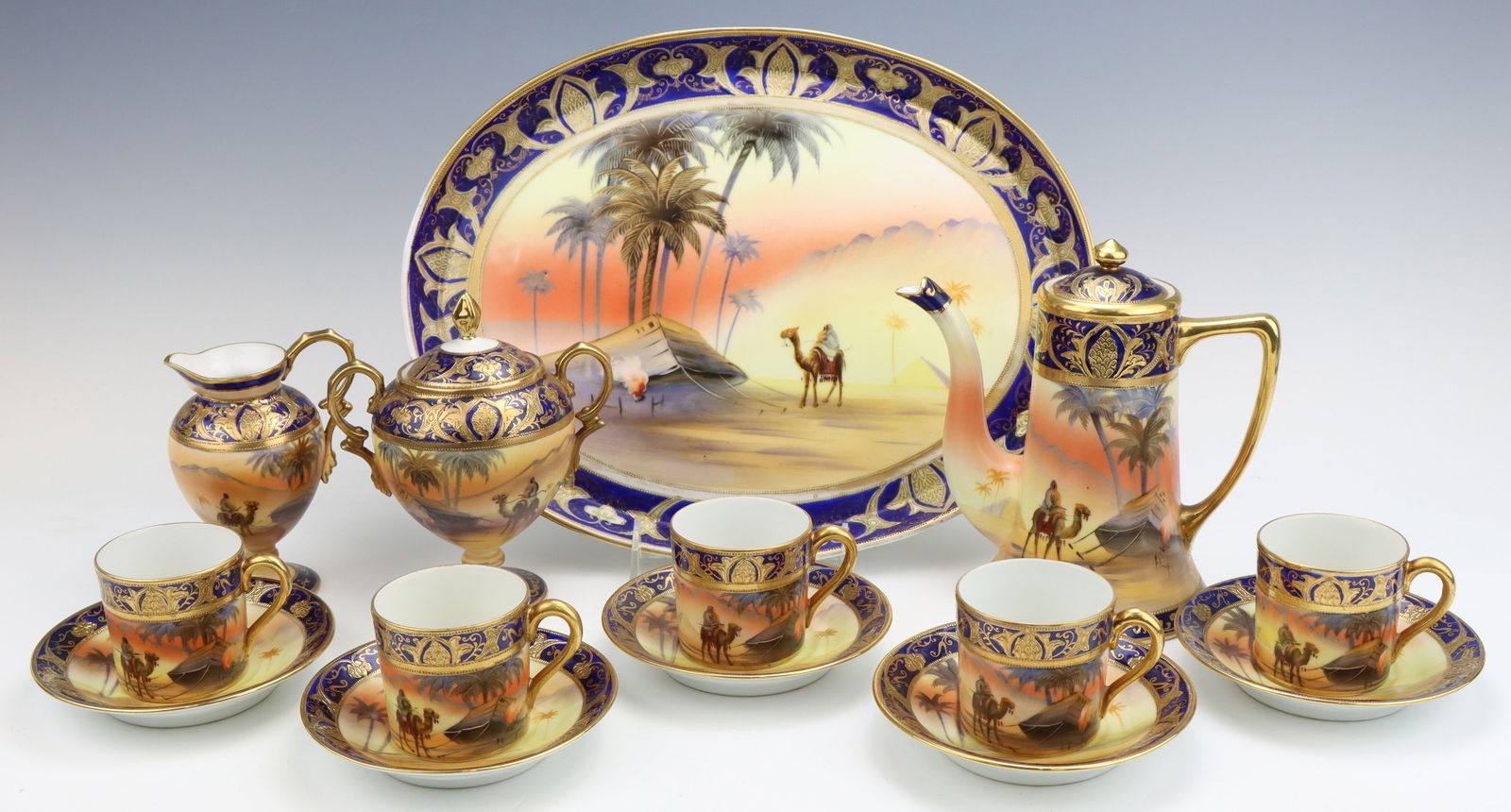 Noritake Chocolate Service: Noritake porcelain chocolate service (includes tray, chocolate pot, 5 demitasse cups and saucers, sugar bowl and milk pitcher), hand painted Egyptian desert pattern, cobalt, gilt decoration, marked, p