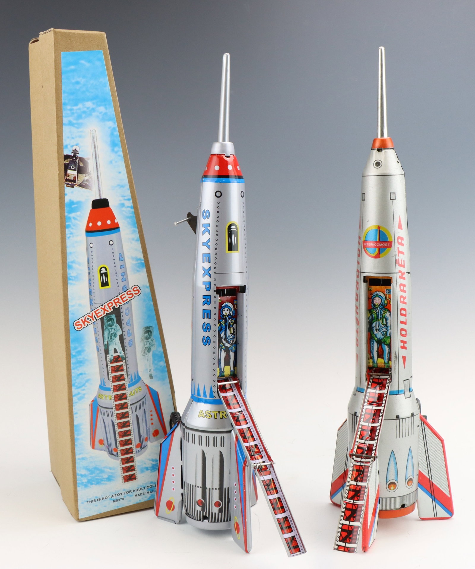 Spaceships: Vintage Hungarian Holdraketa space ship and reproduction Sky Express space ship with original box. Both are friction motion functional. Box measures 4.25”h x 4.5”w x 16”d