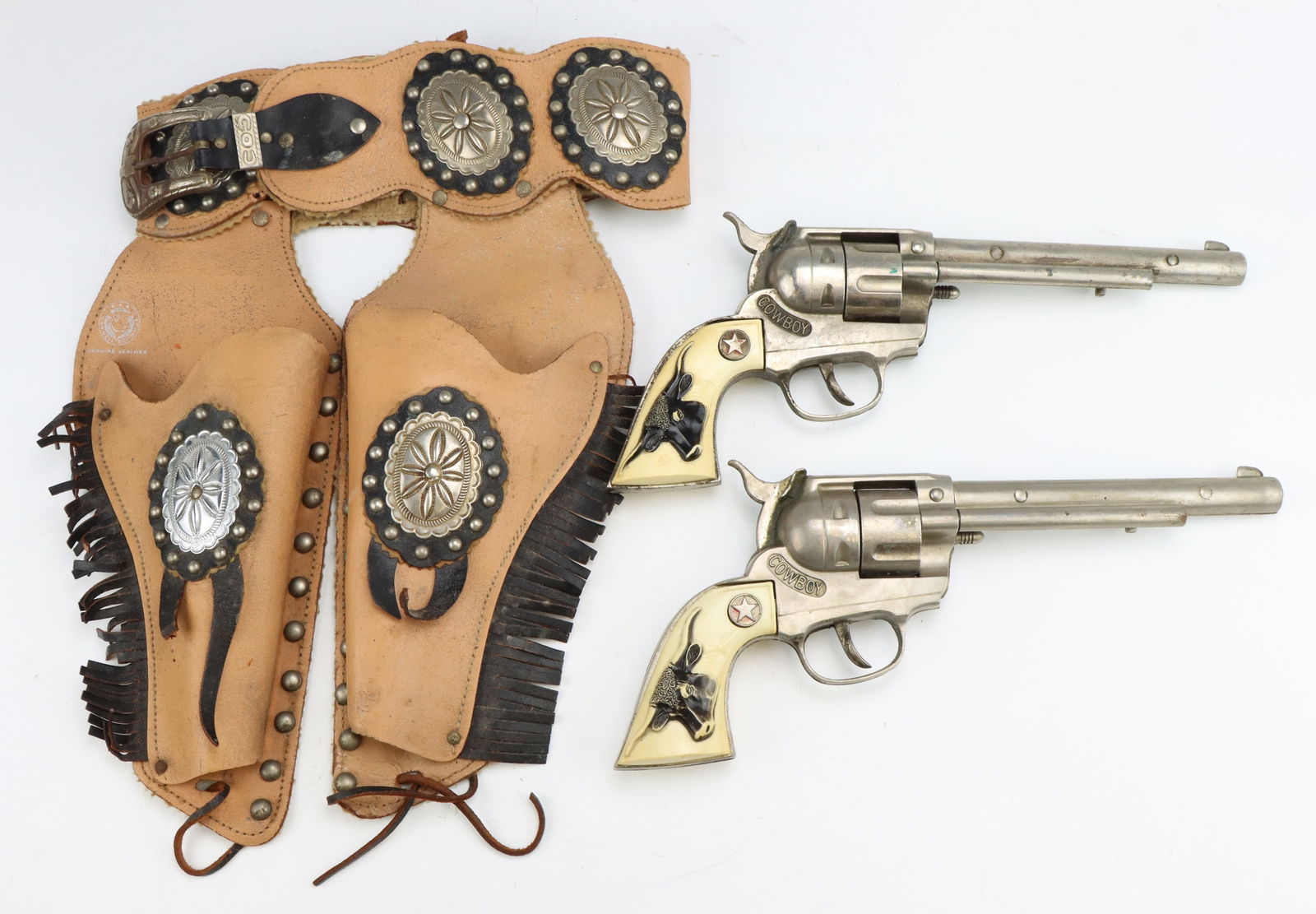 Carnell Roundup Hubley Cap Pistol Set: Carnell Roundup Cowboy set, includes Hubley pistol cap gun pair with longhorn grips, triggers work, wear from age and use, with leather play gun holster, c. 1950's. Pistols measure 5”h x 12&rdqu