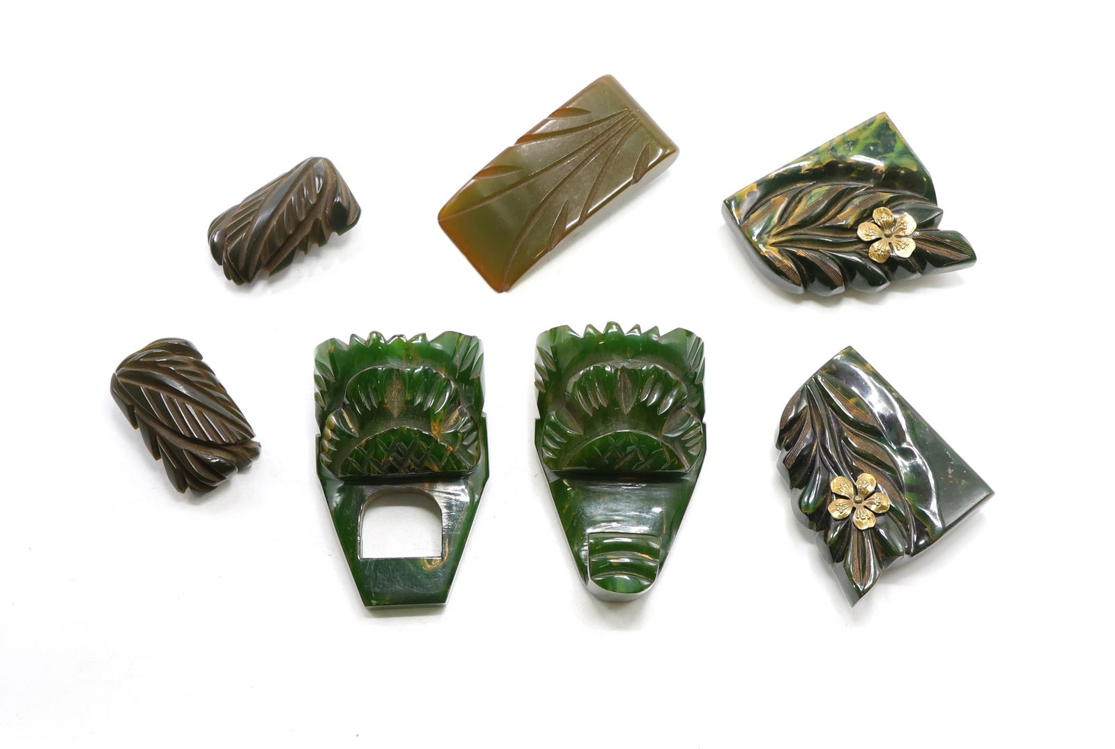 Bakelite Dress Clips: Vintage carved Bakelite dress clips in shades of brown and green. Includes floral and foliate designs. Largest clip measures 2.5”h