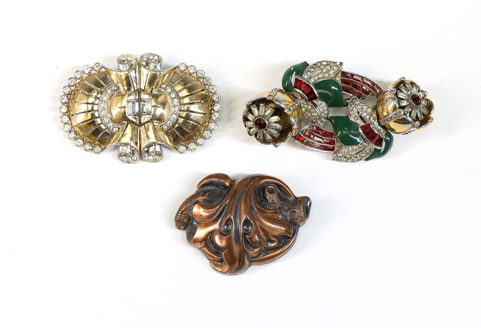 Coro and Duette Style Metal and Rhinestone Brooches: Coro brooch featuring a copper tone floral design with a marked back, (2) duette style rhinestone brooches, one gold tone with clear rhinestones and the other with red, green, and clear rhinestones in