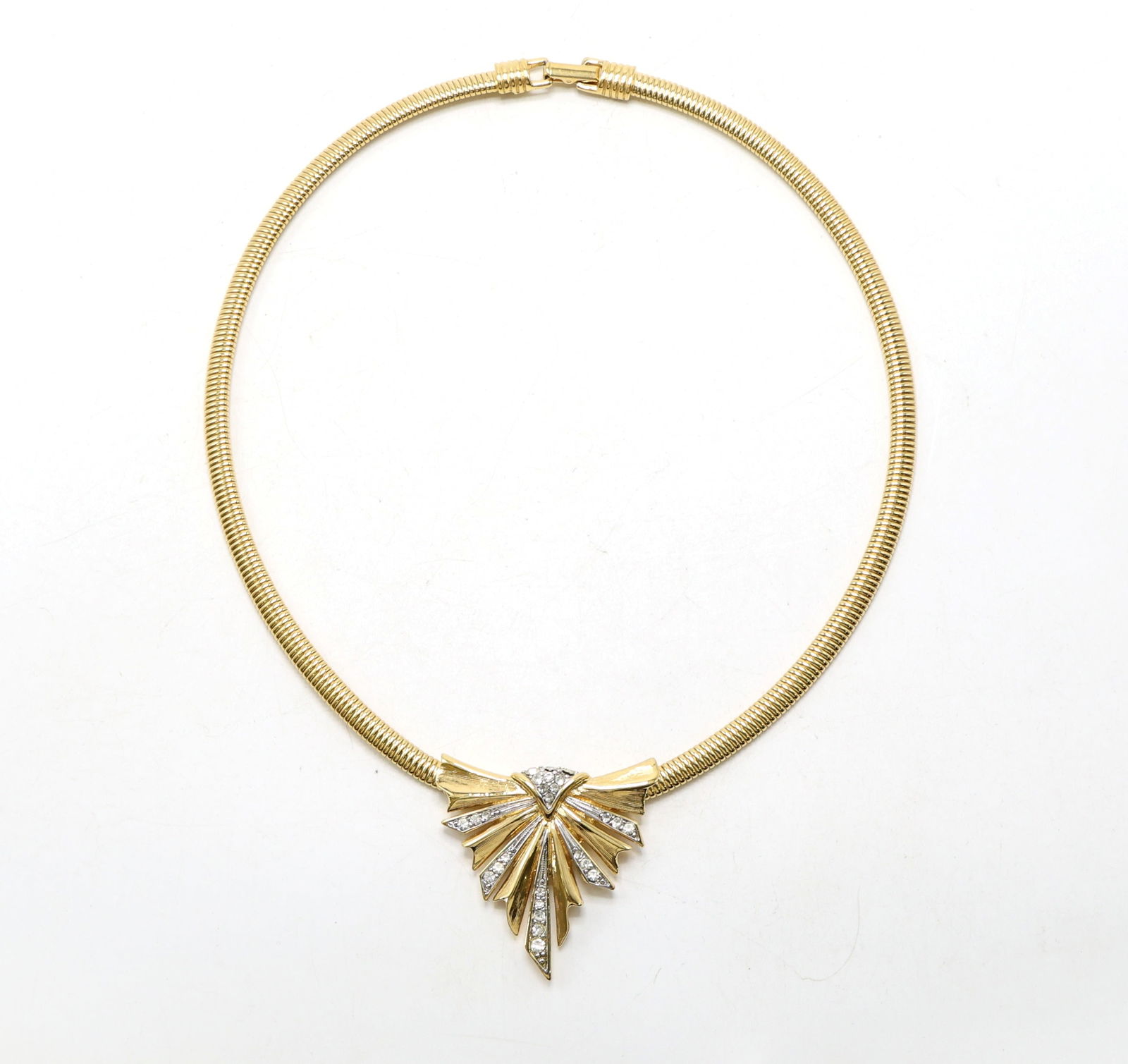 Trifari Gold-Tone Necklace with Rhinestone Pendant: Trifari gold-tone necklace featuring a textured snake chain design with a central pendant in a geometric fan motif, accented with clear rhinestones. Includes a secure fold-over clasp marked 'Trifari.'