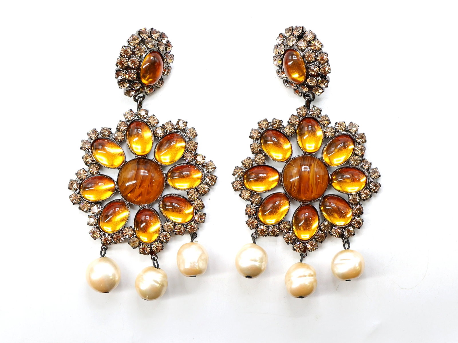 Lawernce VRBA Earrings: Lawrence VRBA amber-colored stones in floral settings. Designed with faux pearl drops and metallic backings. Earrings measures 4”