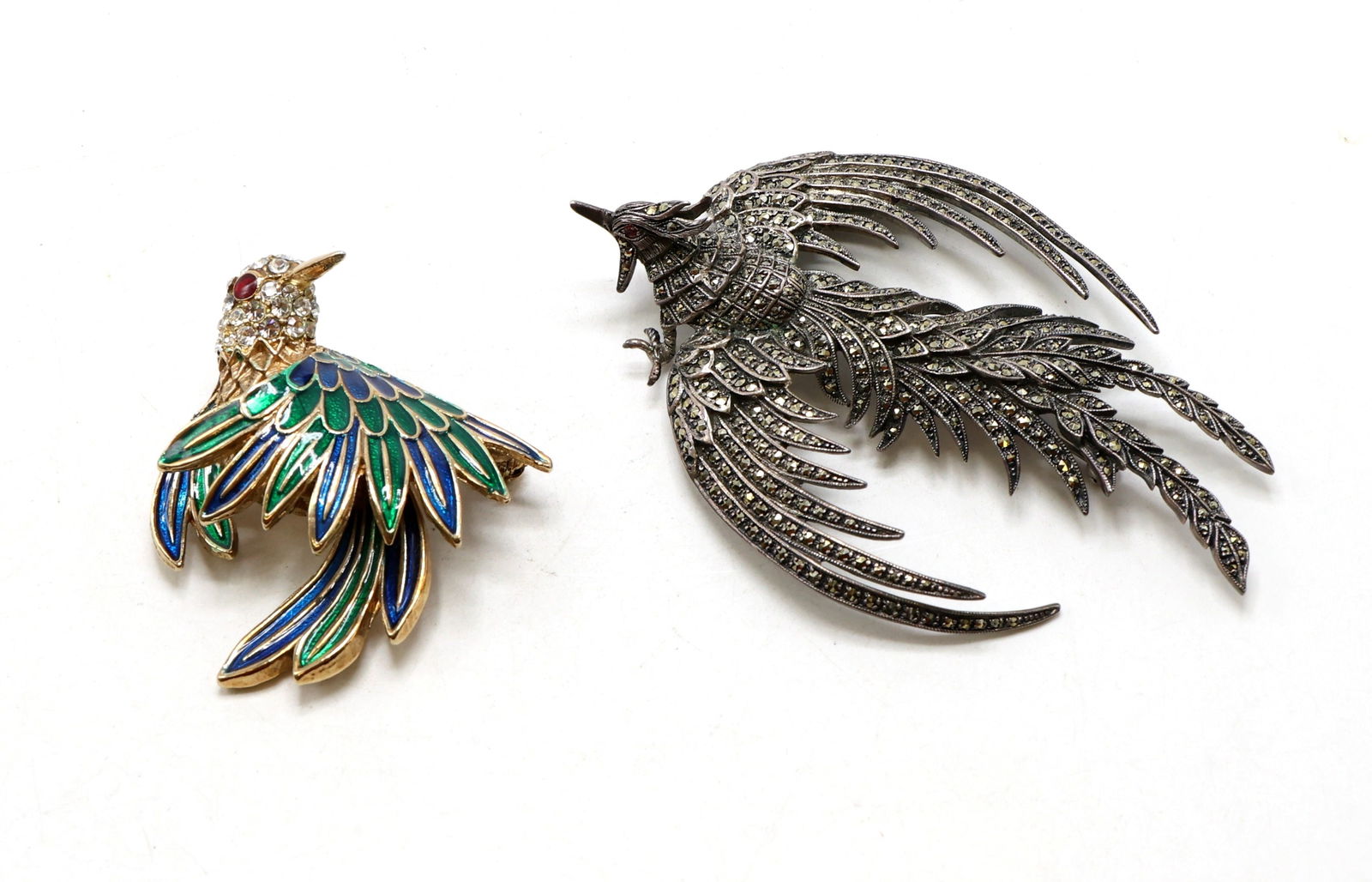 D'Orlan Enamel Bird Brooch and Silver-Toned Marcasite Bird Brooch: D'Orlan brooch featuring multi-colored enamel feathers in green, blue, and gold-tone with a rhinestone-accented head and red rhinestone eye. Also, includes a silver-toned bird brooch adorned with marc