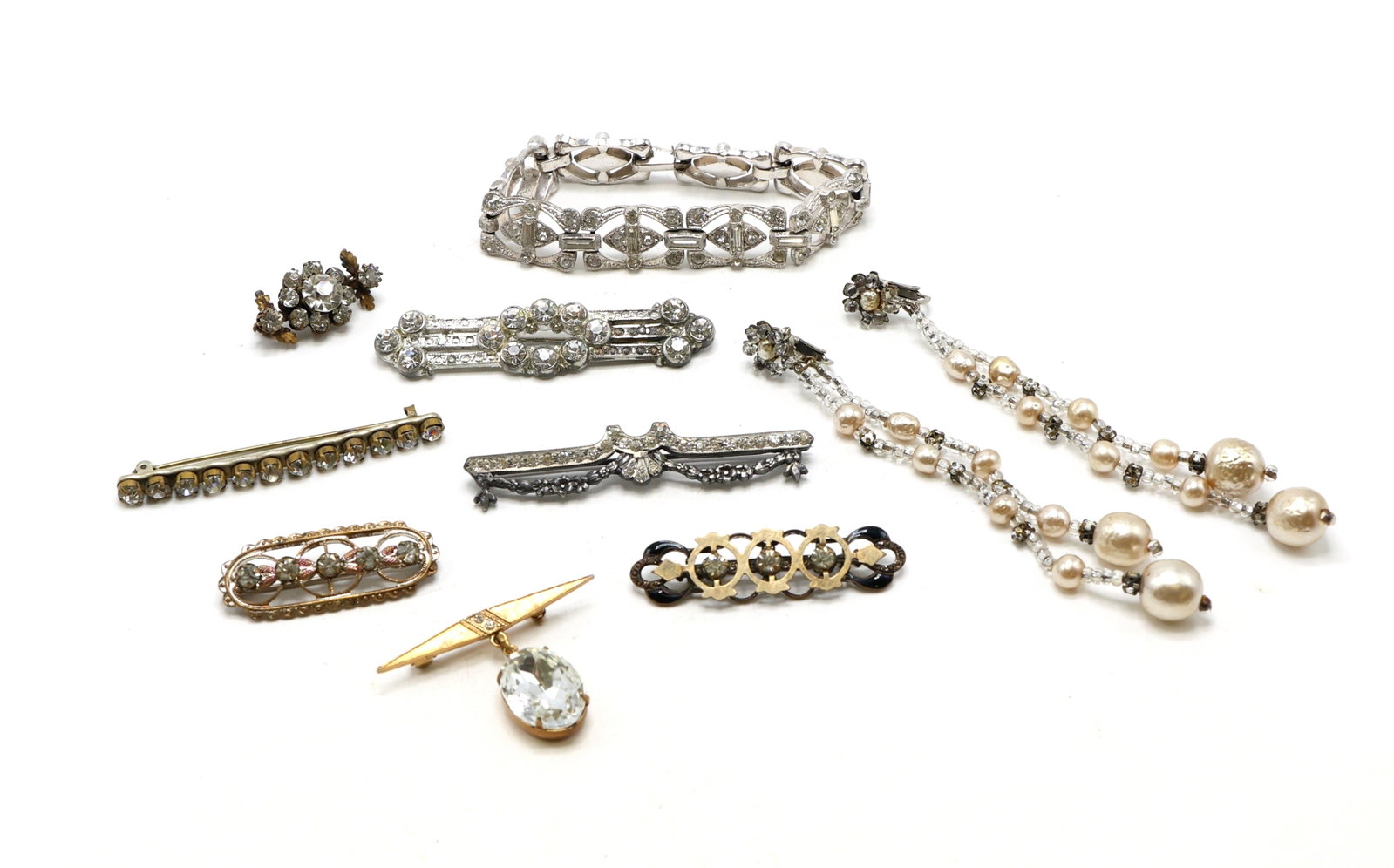 Costume Jewelry: Costume jewelry, including a silver-tone bracelet, brooches with rhinestones, gold-tone brooch, and a pair of pearl and rhinestone earrings. Includes nine pieces total. Bracelet measures 7”, ear