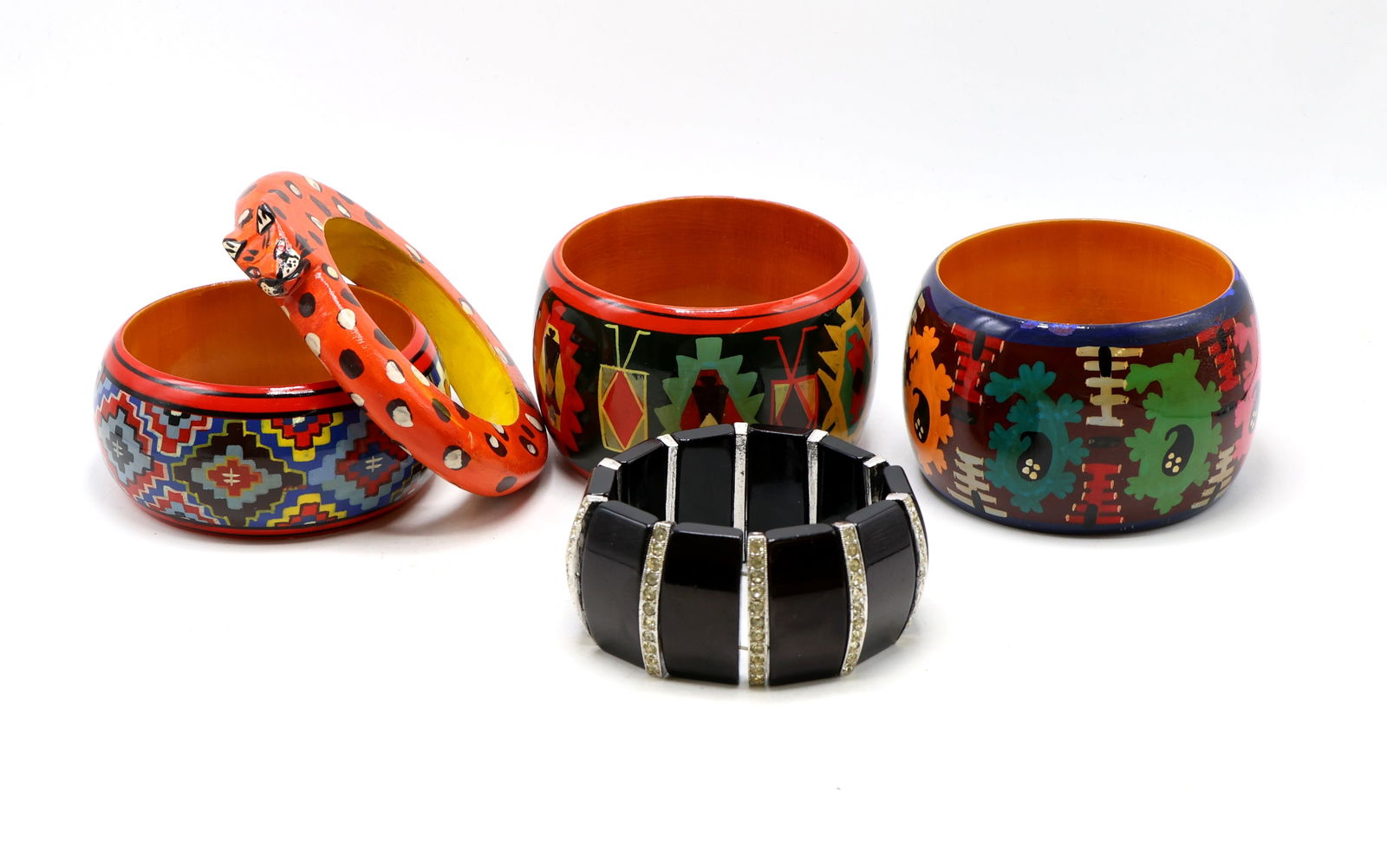 Hand-Painted Wooden and Plastic Bangles: Three hand-painted wooden bangles with geometric patterns, one orange and black polka-dot wooden bangle with animal head, and one black segmented plastic bangle with rhinestone accents. Largest bracel