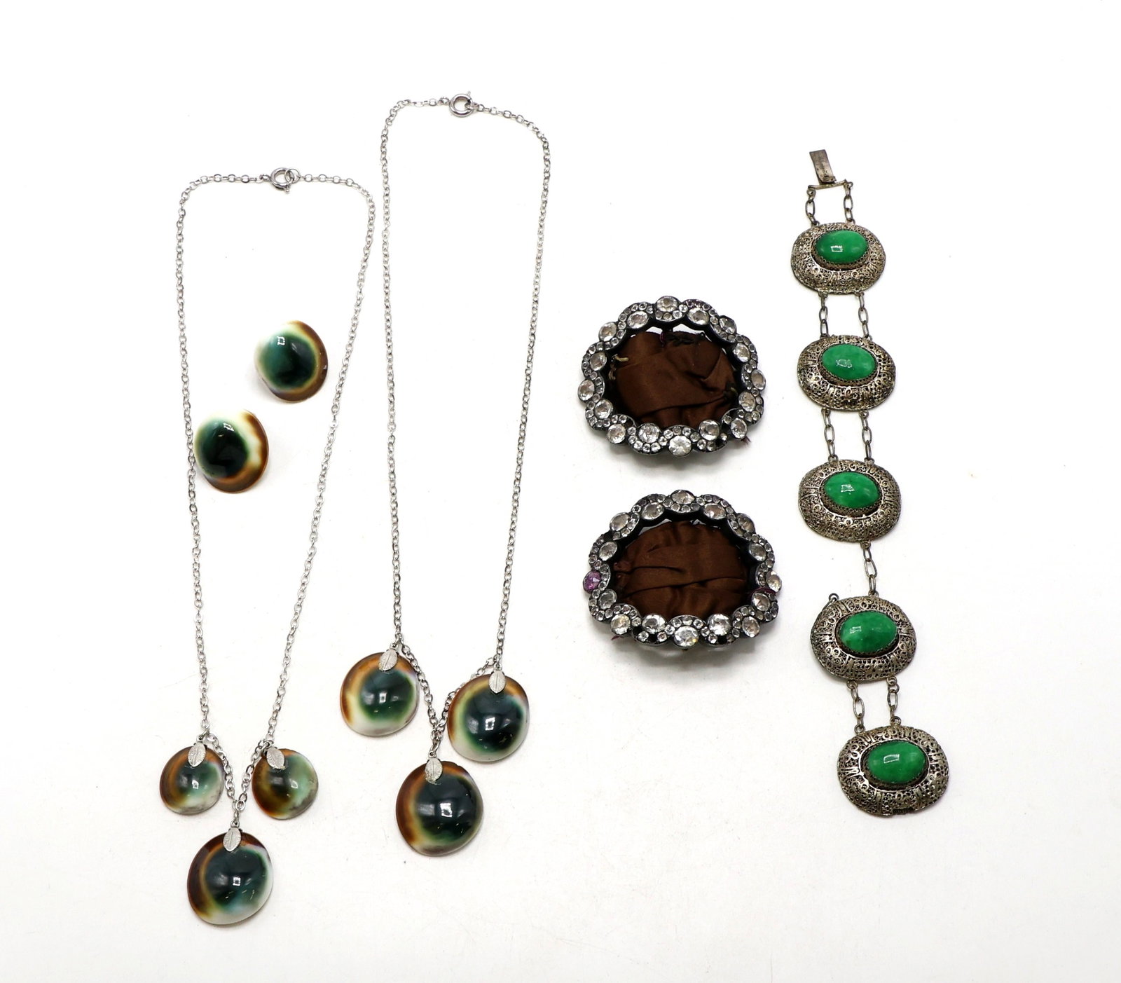 Costume Jewelry: Collection includes two necklaces and matching clip earrings featuring cabochon glass beads, a pair of rhinestone-embellished pins with brown backing, and a metal bracelet with green cabochons set in 