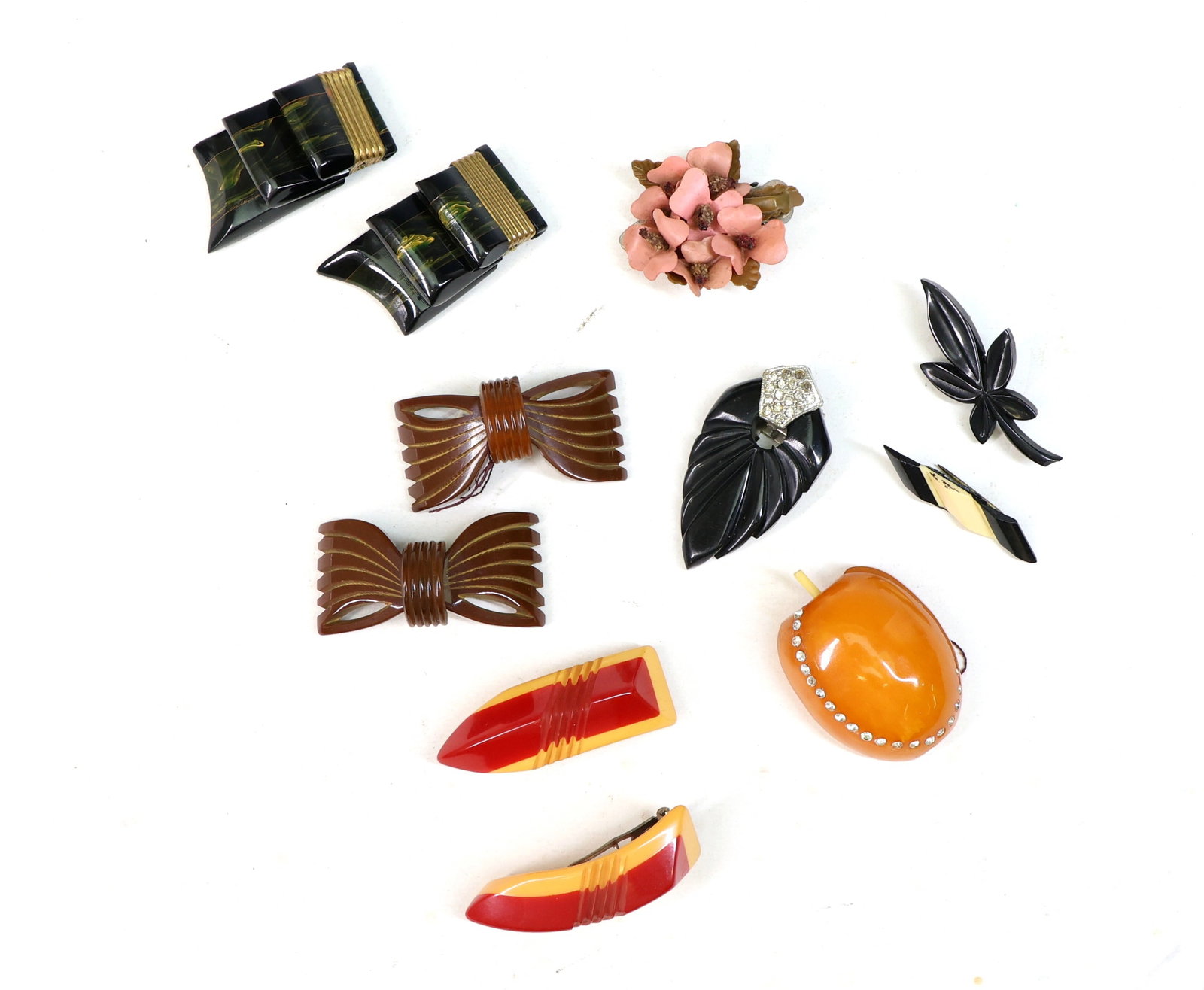 Decorative Pins and Dress Clips: Decorative pins and dress clips, black leaf clip with rhinestones, orange apple-shaped clip, brown bow clips, red and yellow clips, floral clip with pink flowers, and additional black and brown design