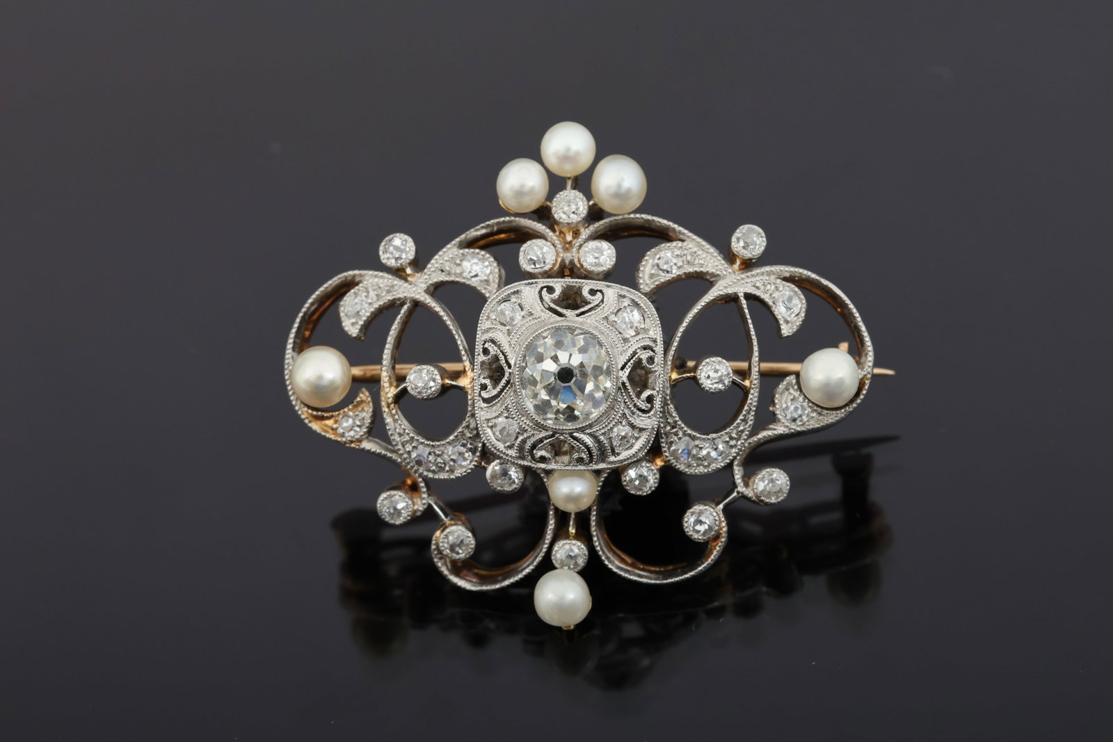 Platinum on WG Diamond Pin: Edwardian style platinum on 10k yellow gold brooch with a 1.0 carat oval cut diamond at center, accented by approx. 2.0 carats of diamonds and six pearls. 1.25" and 6.8dwt