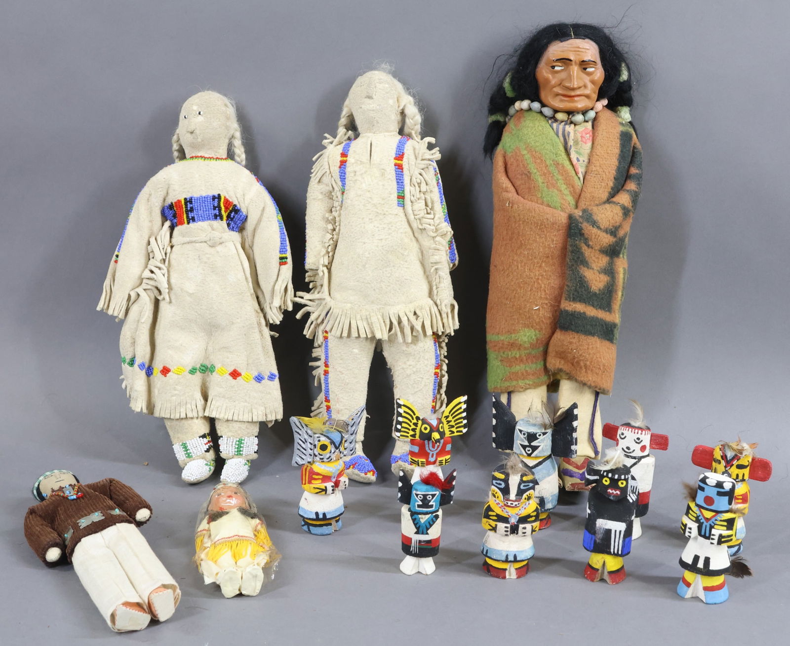 NATIVE AMERICAN DOLLS.: LOT. 13 1/2" Unmarked Male "Skookum" doll. 8" Male "Navajo" doll. 5" Unmarked painted bisque female child doll. (9) 3" - 4" "Kachina" wooden dolls. Some marked - Crows, Owl, Hunter, illegible. (Age lo