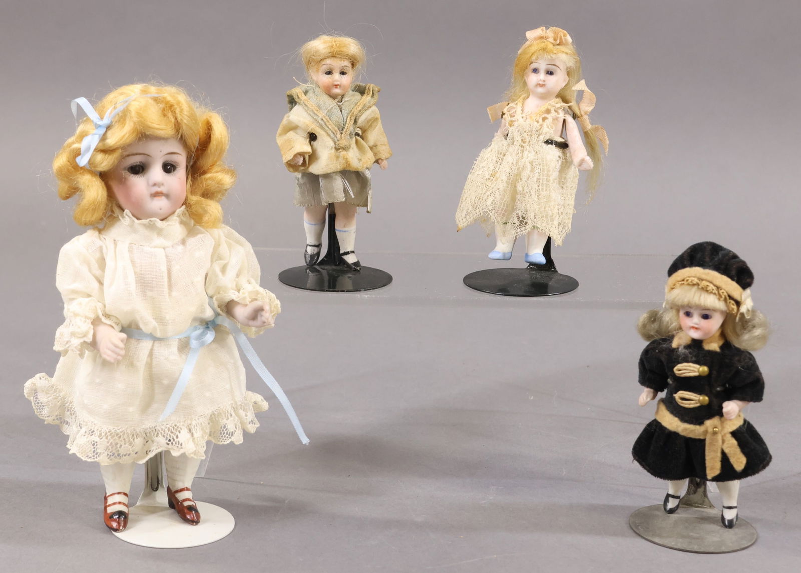 GERMAN ALL BISQUE DOLLS.: LOT of (4) Dolls with blonde mohair wigs, closed mouths, 5 pc. bodies with painted shoes/socks. They are all dressed in antique clothing. 3 1/2", 3 1/2", 3 1/2" Dolls with stationary blue eyes. 6" Dol