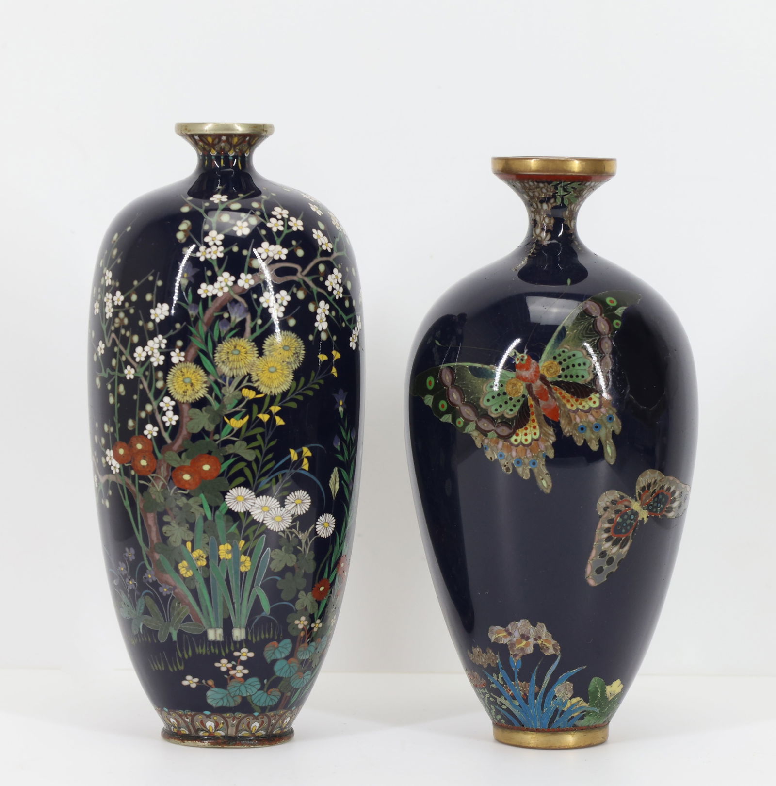 Japanese Cloisonne Vases: Meiji - Taisho era complementing silver wire cloisonne vases, one depicting butterflies in flight over flowers, with a wisteria upper border, the other depicting assorted flowers, with a ruyi and flor