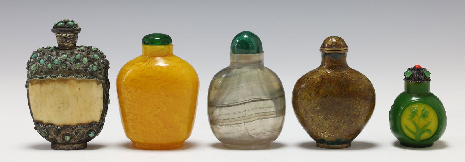 Chinese Snuff Bottles: (5) Chinese snuff bottles including a silver mounted bone bottle set with turquoise cabochons, an amber glass bottle with swirling striations, a banded agate bottle with malachite stopper, a yellow br