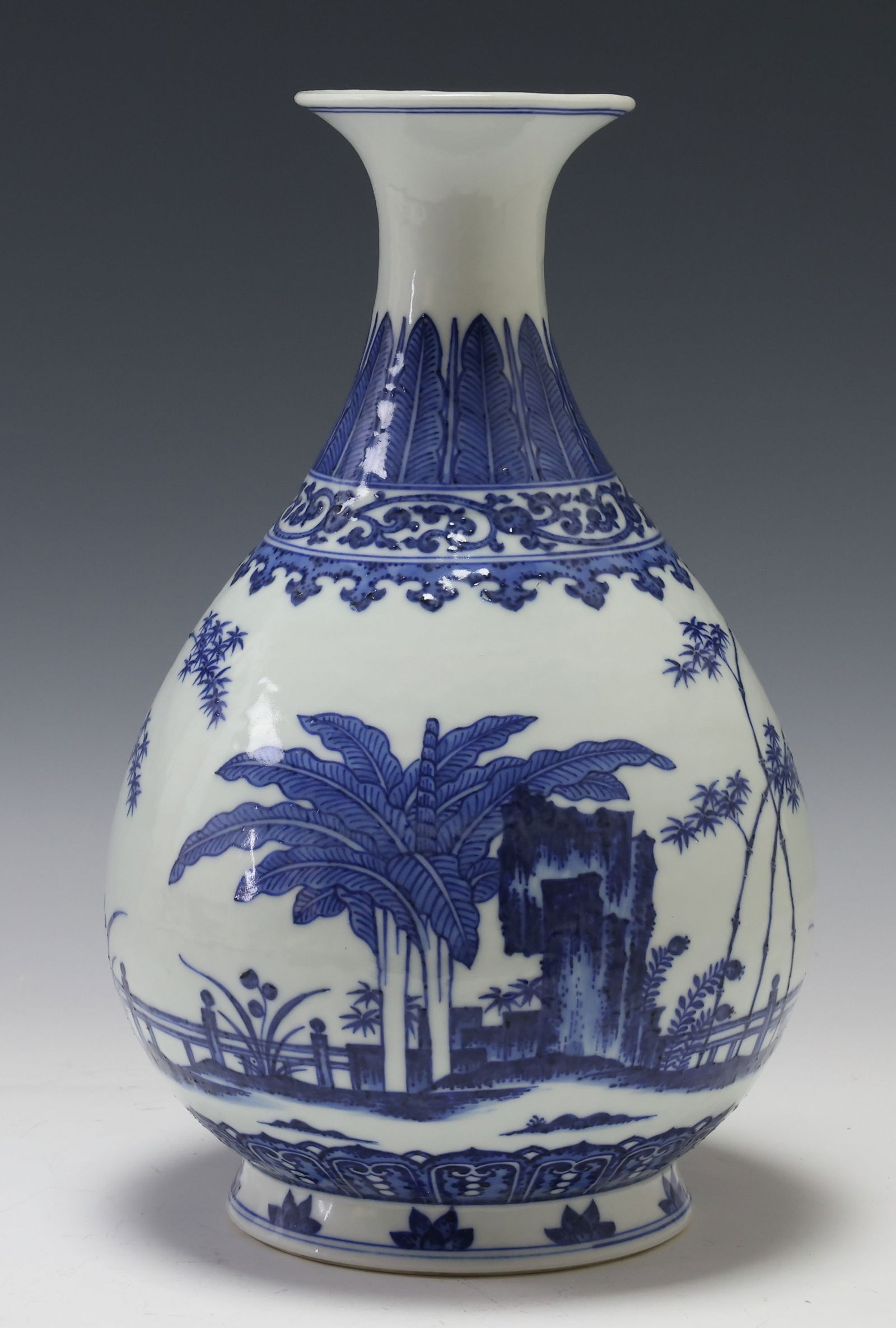 Chinese Blue and White Porcelain Pear Vase: Qing era porcelain pear shaped or yuhuchun vase with blue and white decoration depicting a fenced garden scene with rock formations among assorted foliage including bamboo and plantains, featuring a l