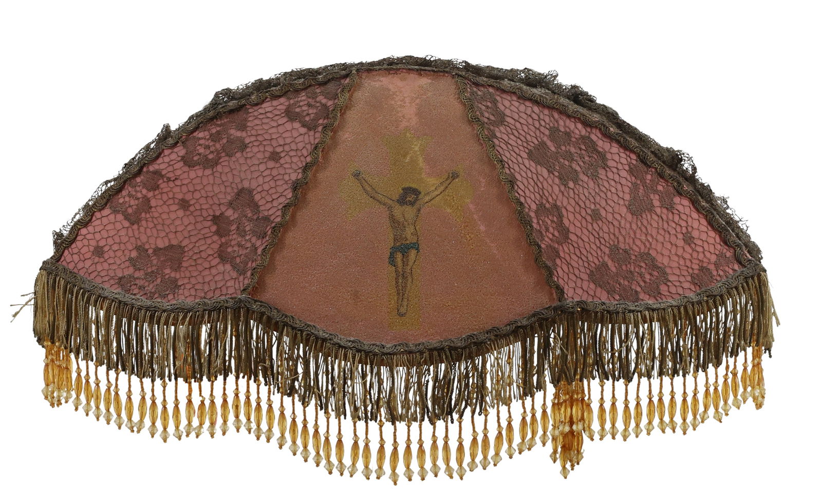 Victorian Casket Lamp: Half dome lampshade having a wire frame covered with textured pink fabric, lace overlay made of metallic thread, center with imaginary of Jesus on a cross and beaded fringe. On reverse, two u-shaped h