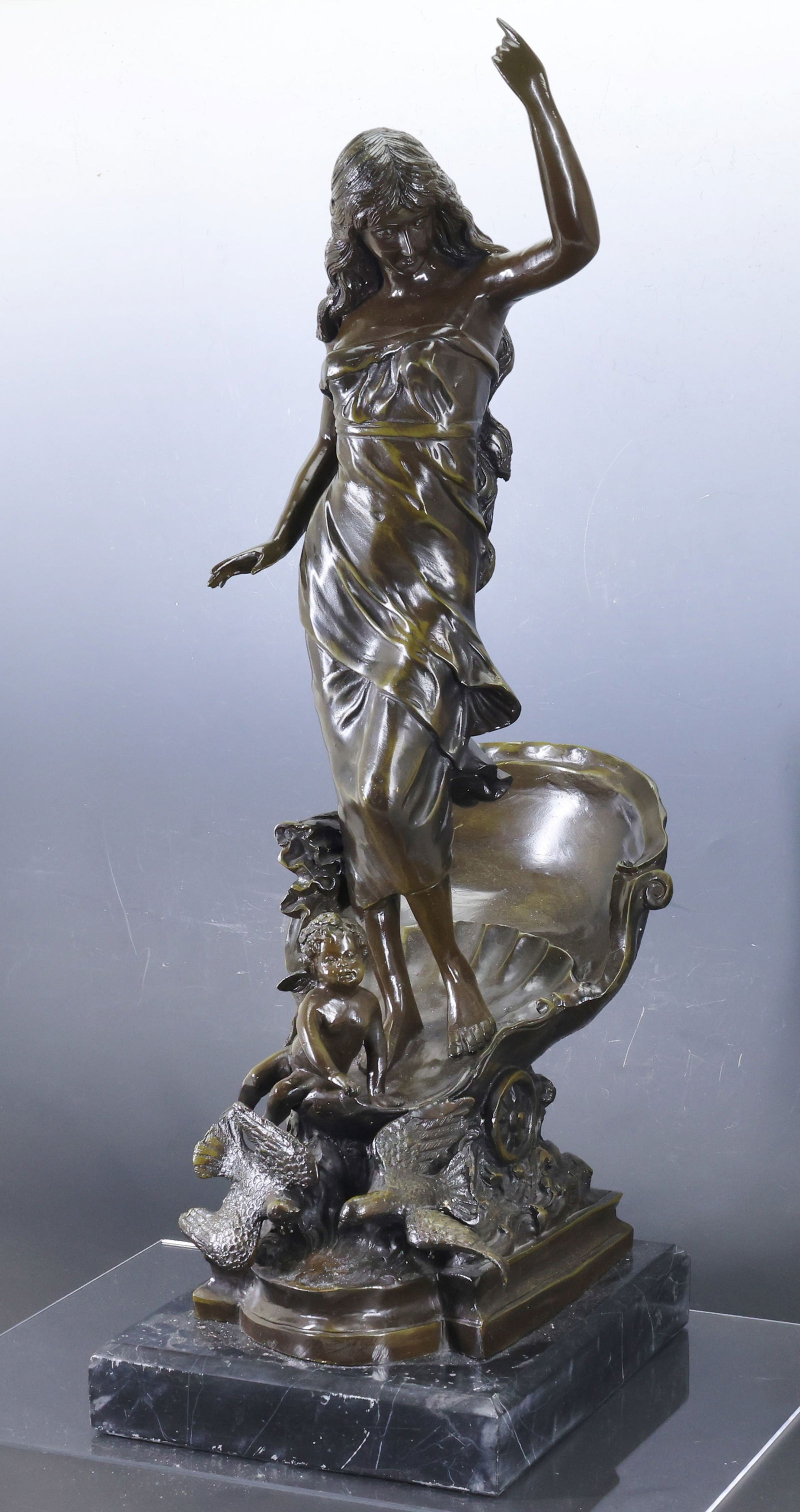 After Auguste Moreau (1834 - 1917): Bronze sculpture, "Le Char de l'Aurore (The Chariot of Aurora)", a depiction of the Roman goddess of dawn in a shell form chariot with a putti and doves, mounted to a marble plinth. No markings noted.