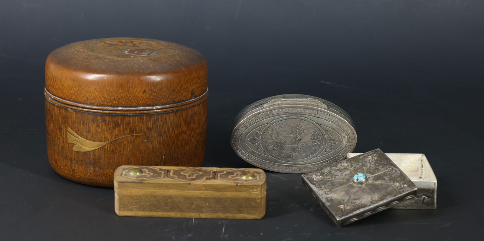 Decorative Boxes: Japanese lacquered wood and inlaid brass cylindrical box with red interior, an oval pewter snuff box engraved with pastoral scene, a Navajo box set with a turquoise cabochon, and a wooden inlaid puzzl