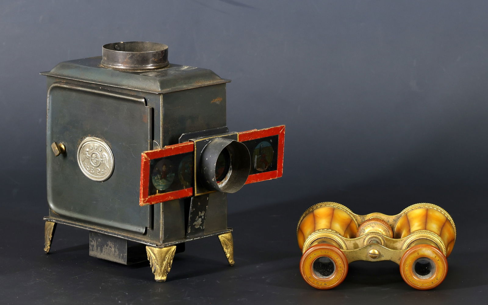 Magic Lantern and Opera Glasses: Late 19th-century tin magic lantern projector with original slides housed in a fitted box, slides featuring various animated and scenic subjects, and a pair of J.E. Caldwell & Co., Paris, opera glasse