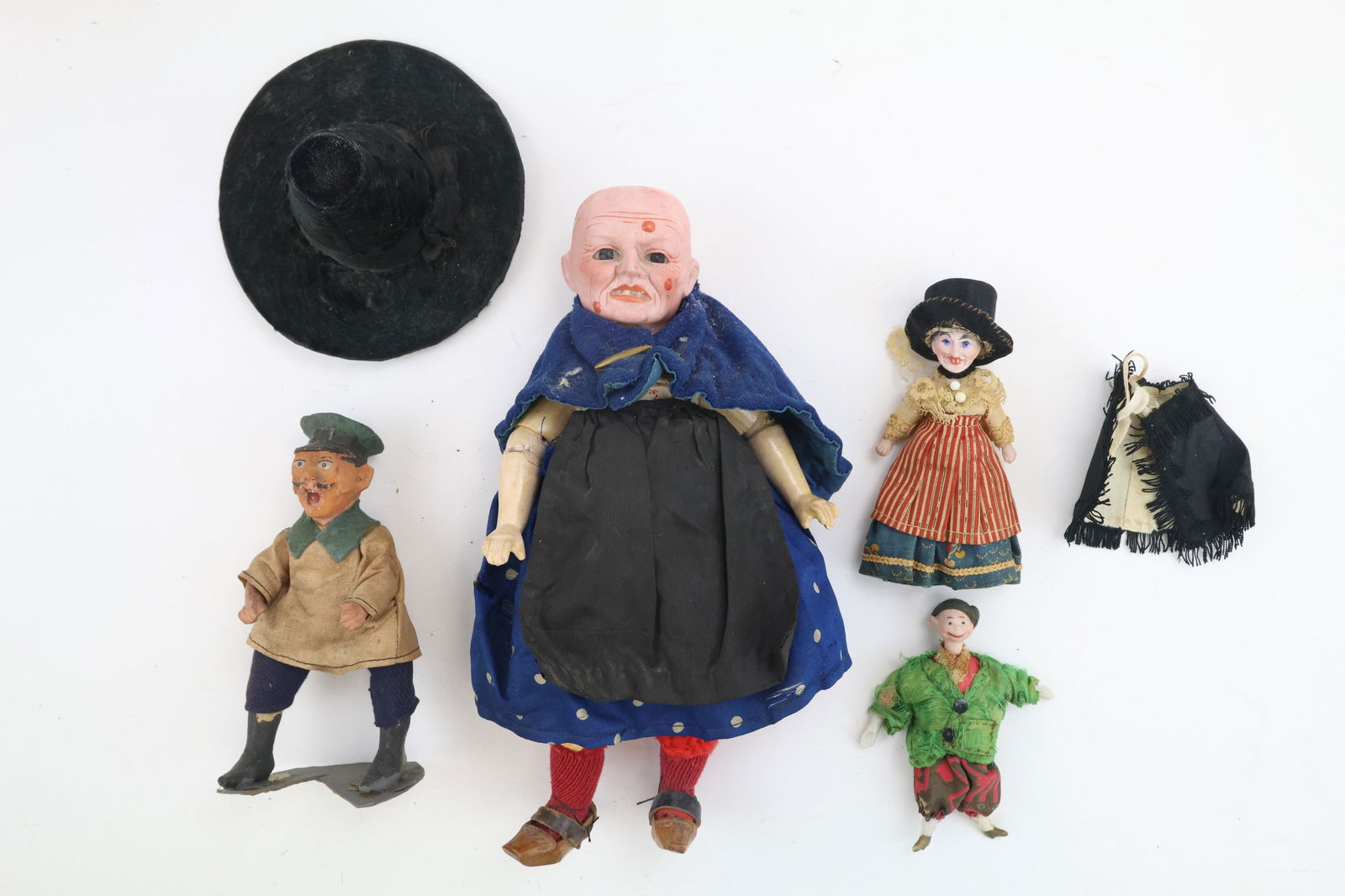 German Bisque Head Character Dolls: Character dolls include a Hexe Witch with jointed limbs, dressed in blue with red stockings and a black hat, 8.5”. Witch dollhouse doll, all bisque, wearing a striped overskirt and black shawl,