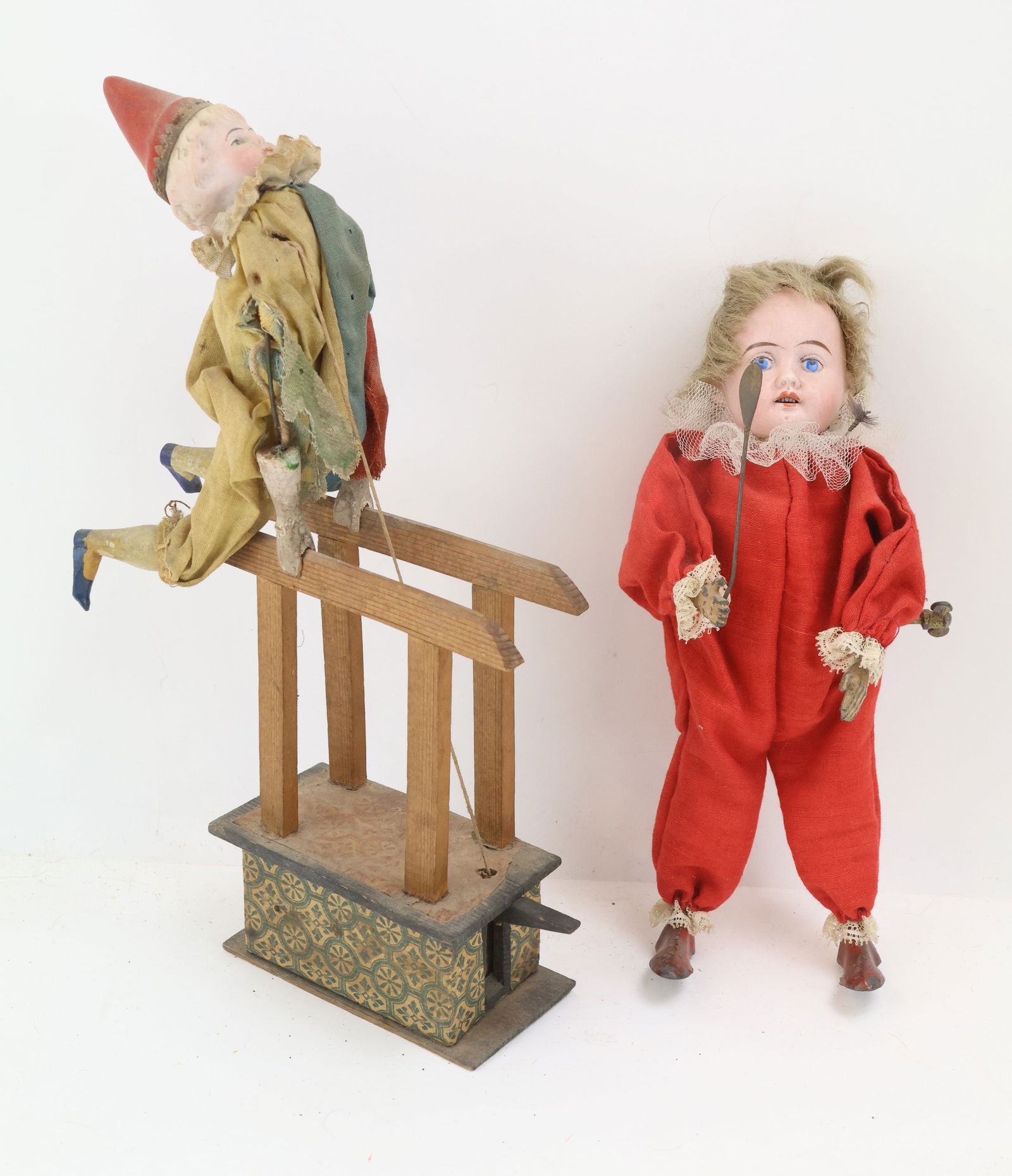 German Bisque Head Doll Toys: 8" wind up clown with metal feet and hands, and an 11" clown that squeals and flips when lever is depressed. Both in working order with age loss and wear.