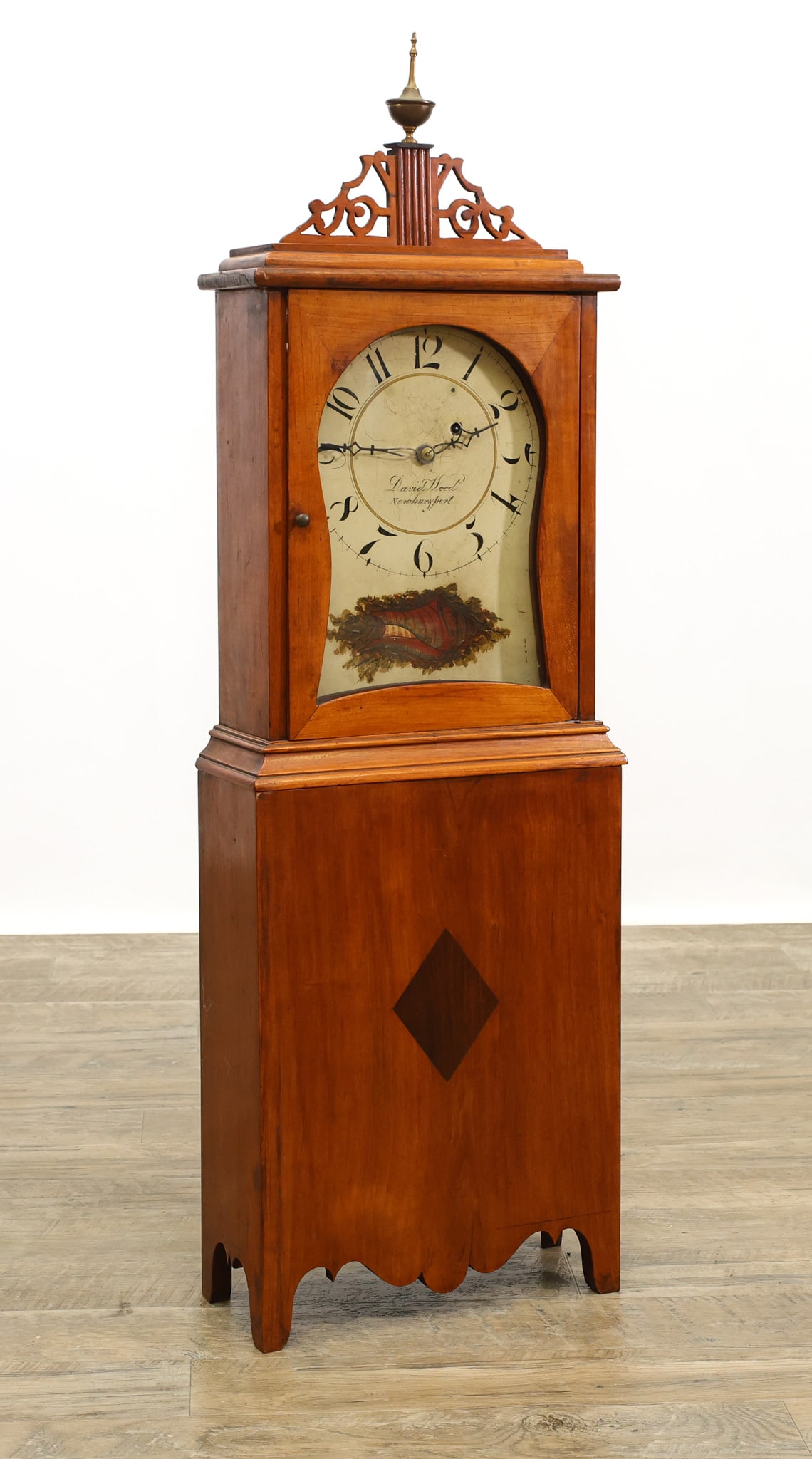 David Wood Newburyport, Massachusetts Shelf Clock: Applewood case with the top having a chimney and brass urn finial flanked by open fretwork on a molded cornice, glass hood door, plinth base with molded top continuing to a shaped skirt and feet. Thir