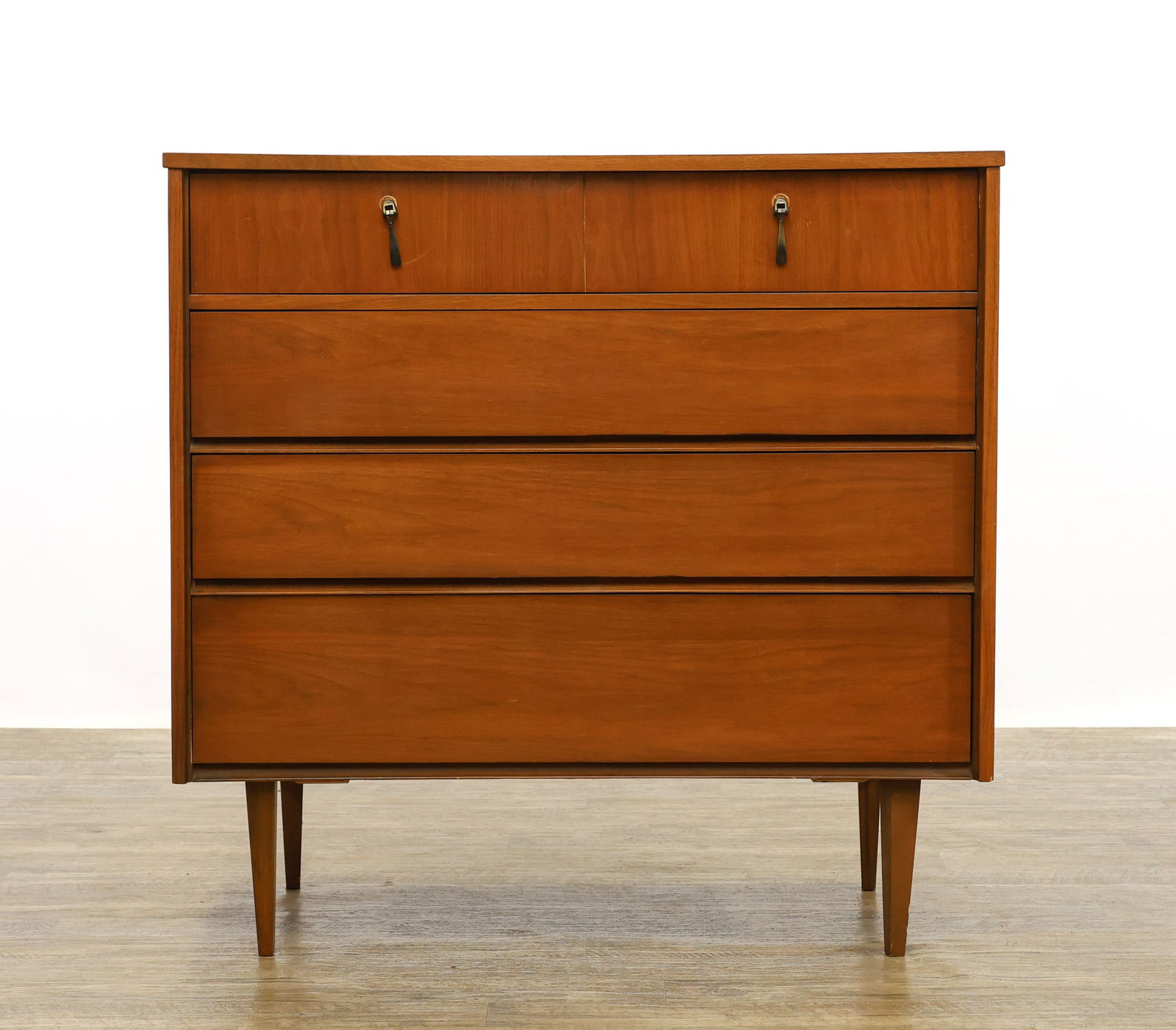 Walnut Tall Dresser: Danish Modern style tall dresser featuring four drawers, the top with brass pulls, and raised on tapered square legs. Scattered surface wear. 40"h x 41"w x 19"d