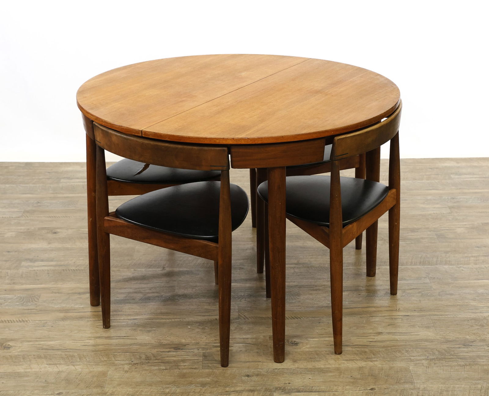 Hans Olsen for Frem Rojle "Roundette" Dining Set: Danish Modern teak dinette set, model 631, including a round extendable table featuring a butterfly leaf and raised on cigar legs, and (4) tripod chairs with cigar legs, floating seats with black viny