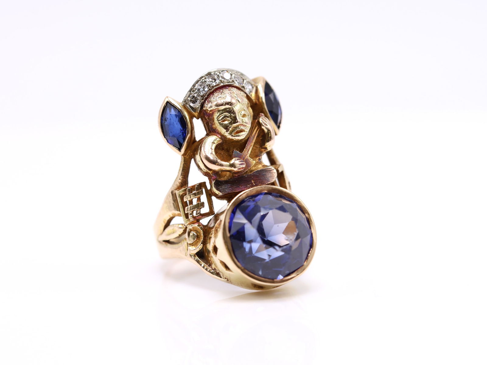 14k YG Sapphire RIng: 14k yellow gold figural Aztec style ring set with an oval cut sapphire approx. 8.00cts exhibiting table abrasion, flanked by marquise cut sapphire accents and round cut diamond accents. Size 7 and