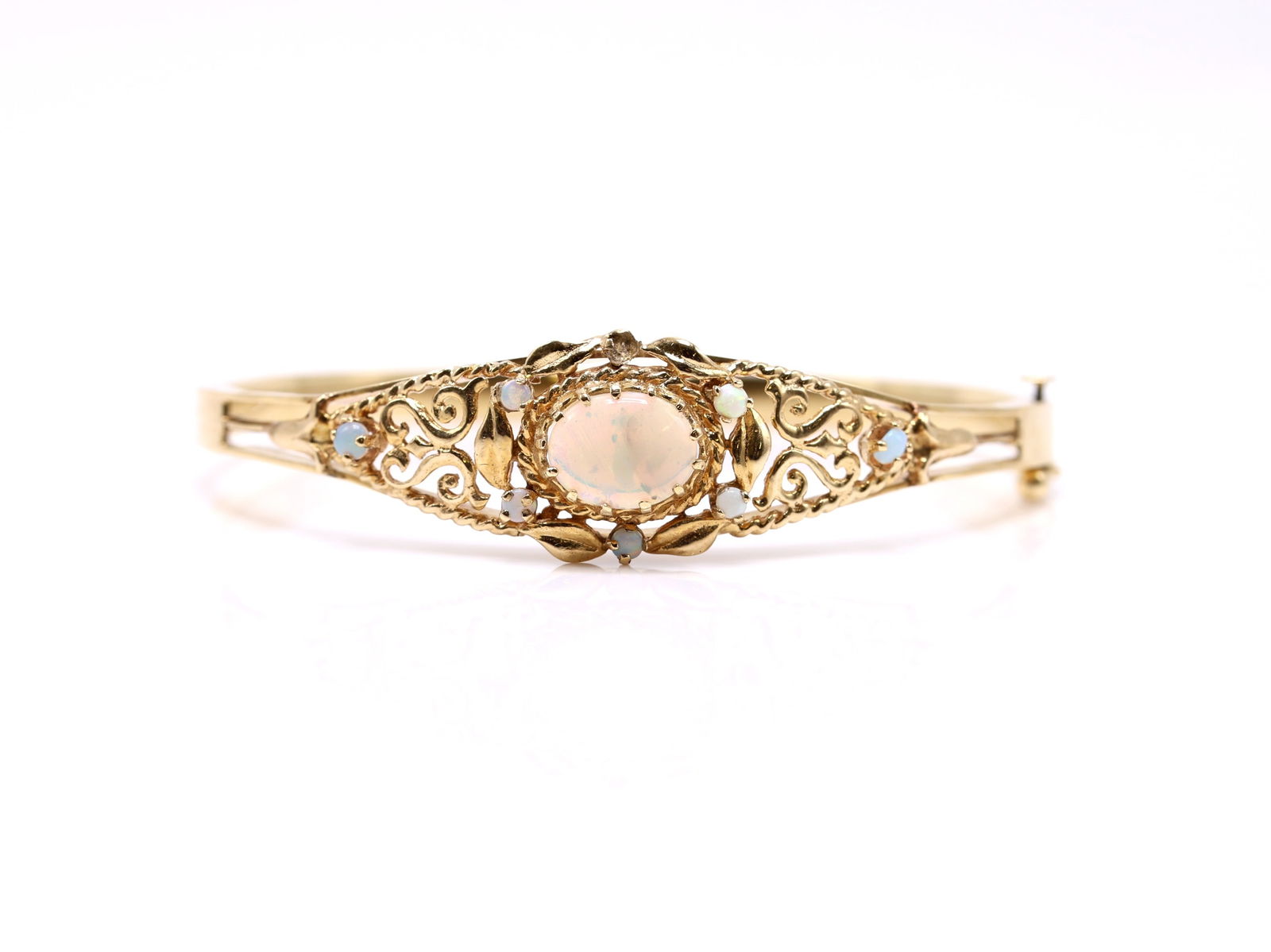 14k YG Opal Bracelet: 14k yellow gold opal bracelet set with an oval cabochon opal measuring approx. 10mm, accented by smaller opals in an openwork mount, one missing. 6.5" and 7.8dwt.